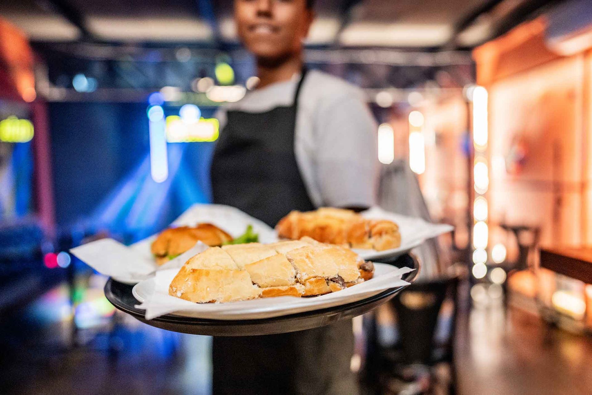 A waiter is holding a tray of food in a restaurant.