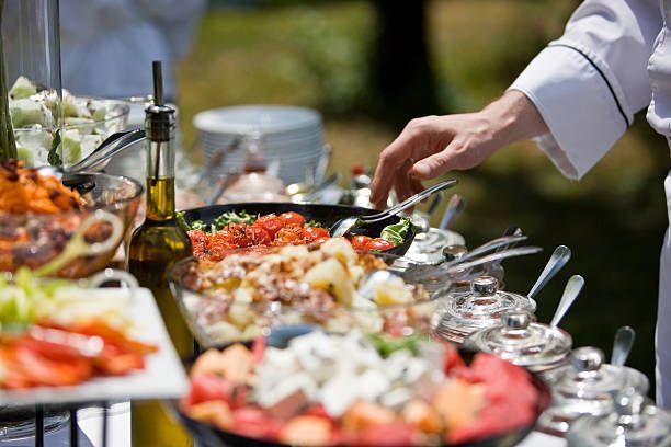 A chef is serving food at a buffet table.