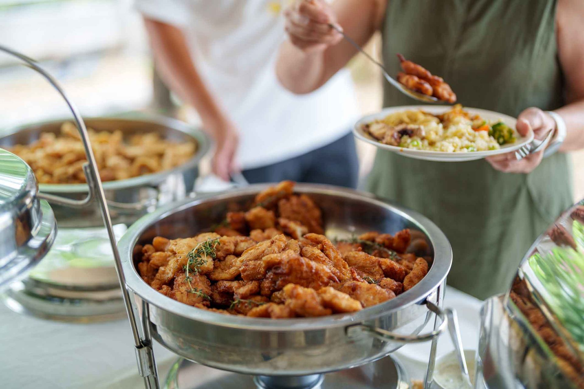 A woman is taking a plate of food from a buffet.