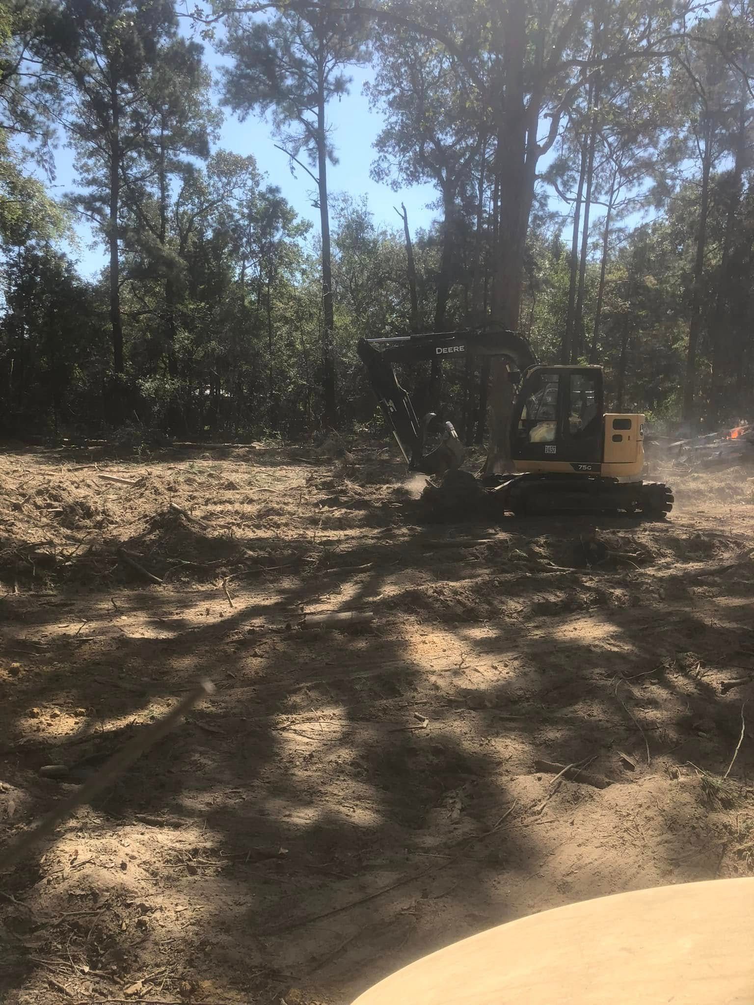 A bulldozer is moving dirt in the middle of a forest.