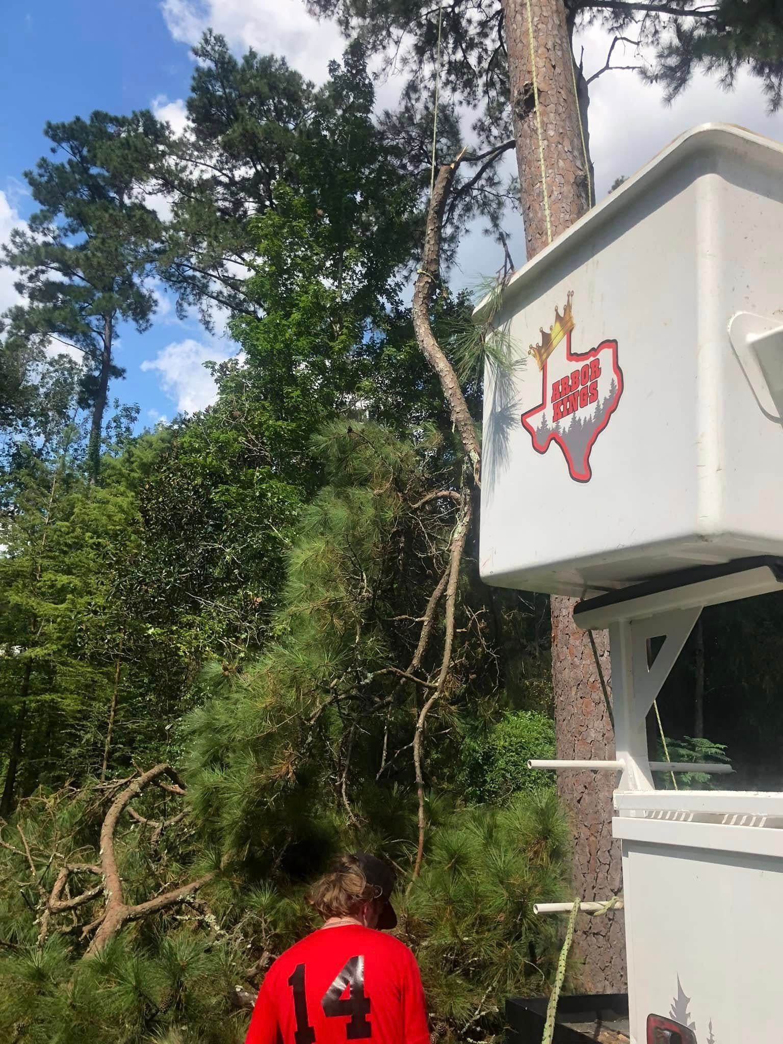 A man in a red shirt is standing in front of a bucket truck.