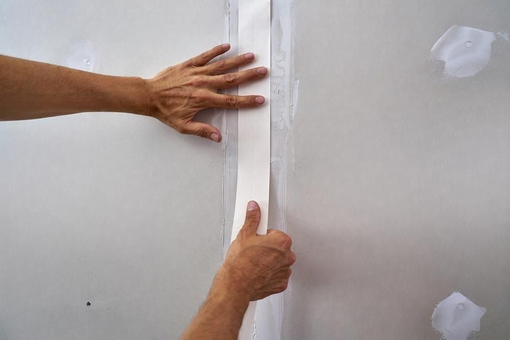 a person is holding a piece of tape on a wall .