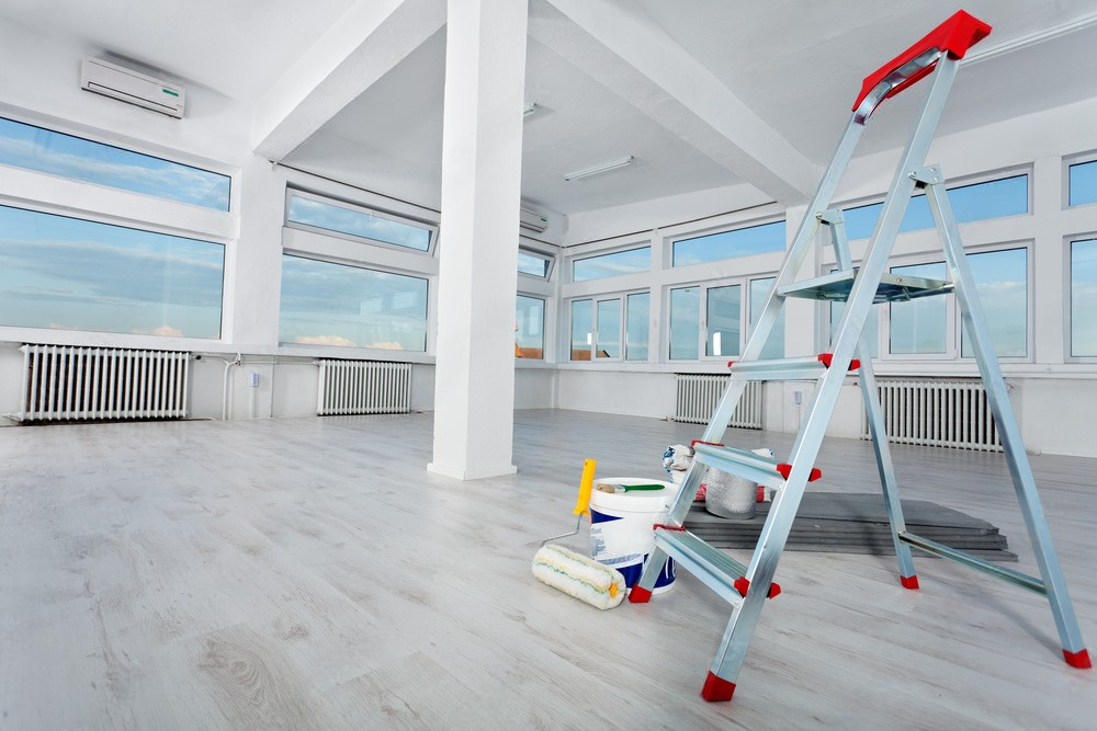 an empty room with a ladder and paint on the floor .