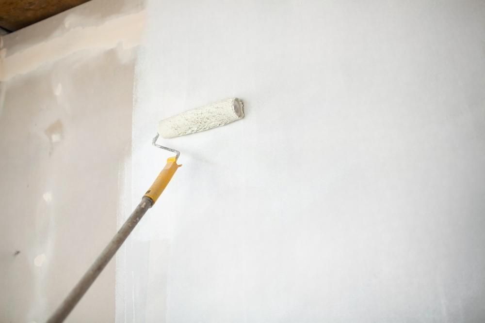 a person is painting a sheetrock with a paint roller .