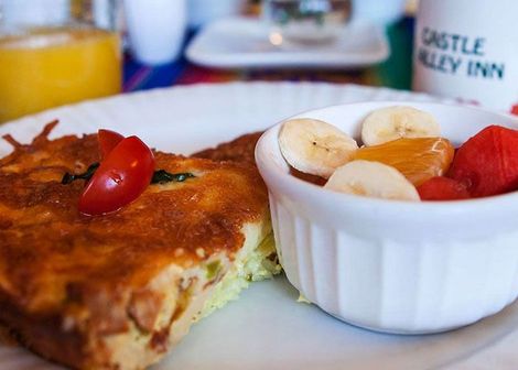 Toast with cherry tomatoes and a bowl of fruit on a breakfast table