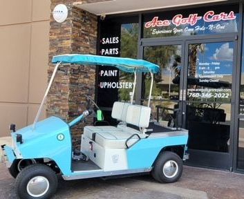 A blue and white golf cart is parked in front of ace golf cars