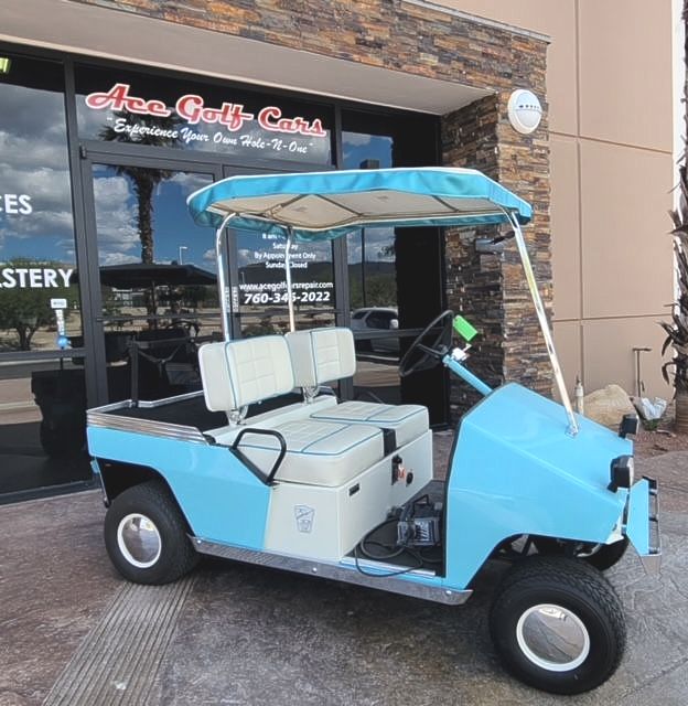 A blue golf cart is parked in front of ace golf cars