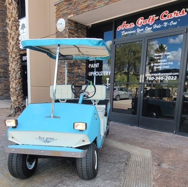 A blue golf cart is parked in front of a store that sells golf carts