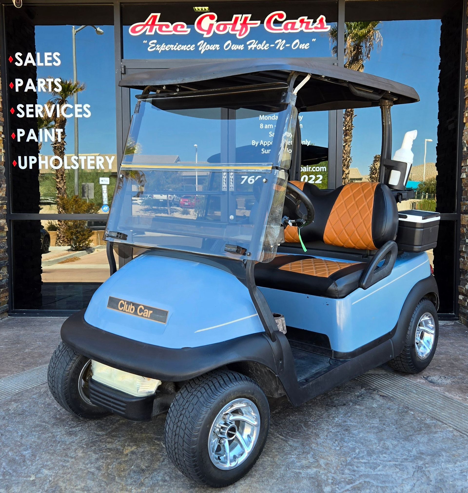A blue golf cart is parked in front of a store that sells golf carts