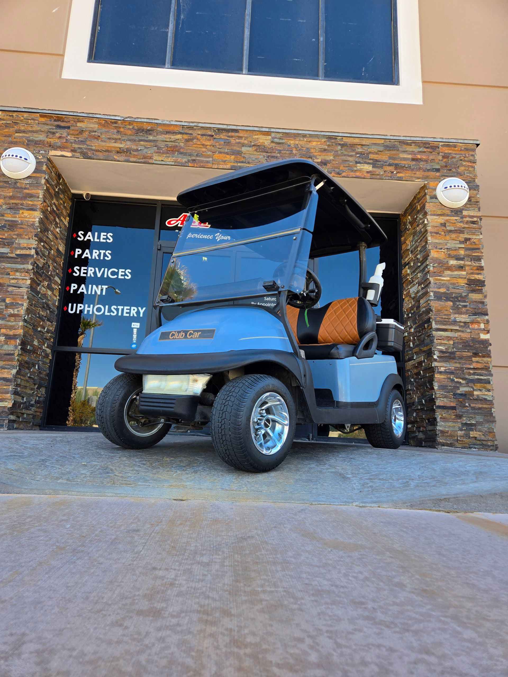 A blue golf cart is parked in front of a building.