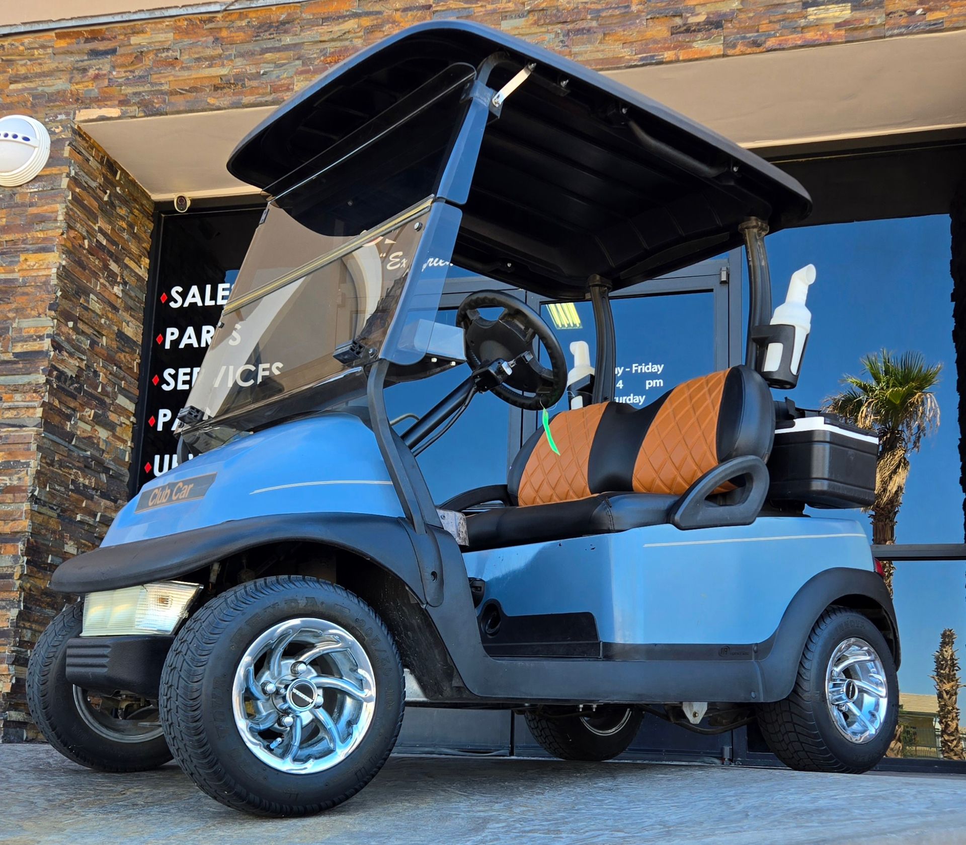 A blue golf cart is parked in front of a store that sells golf carts