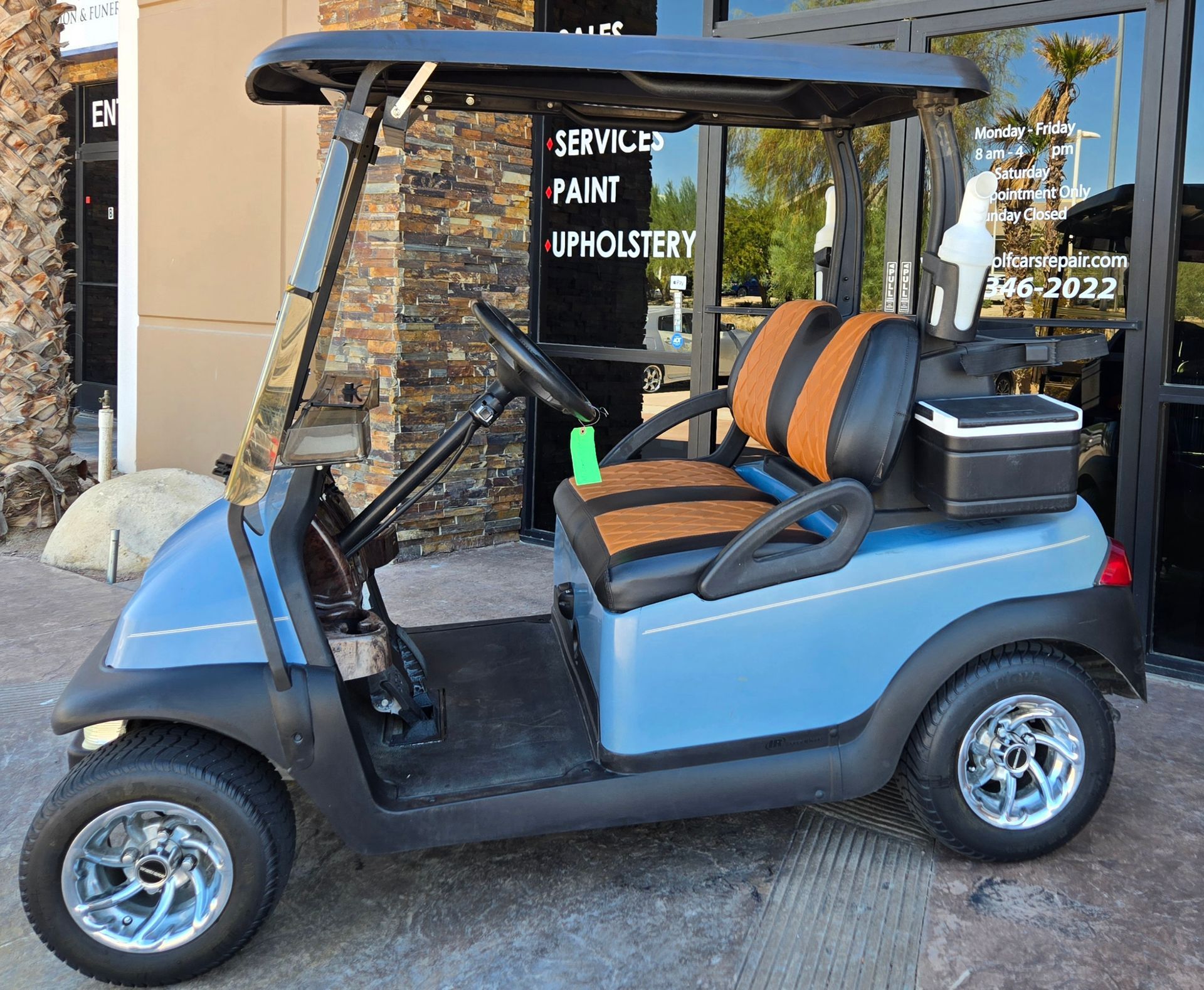 A blue golf cart is parked in front of a building.
