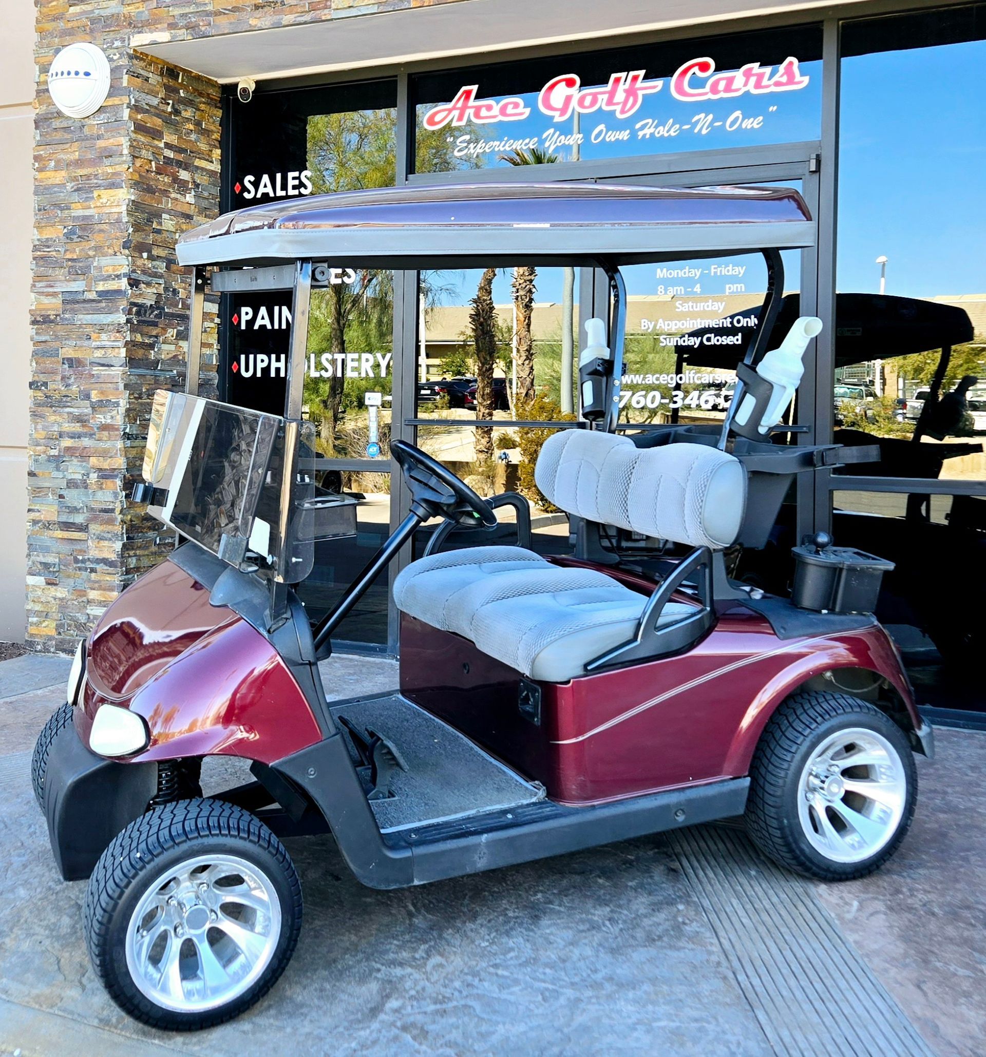 A red golf cart is parked in front of a store.