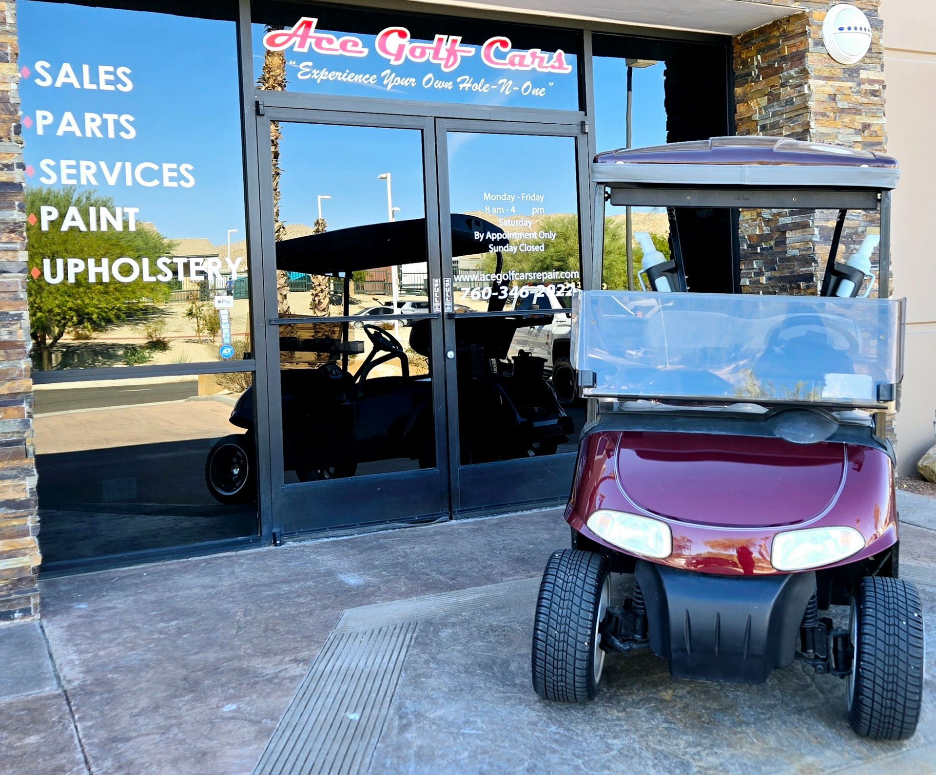 A red golf cart is parked in front of a store that sells golf carts