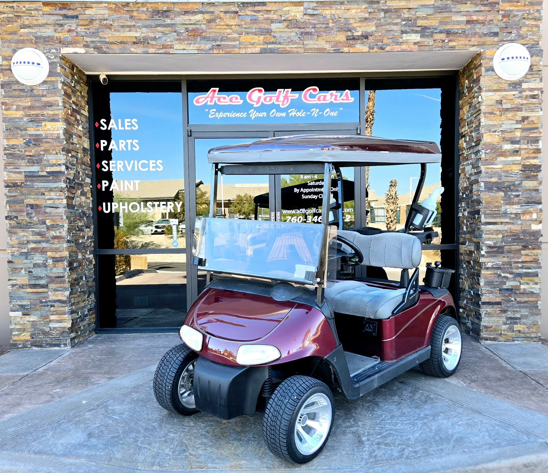 A red golf cart is parked in front of a brick building