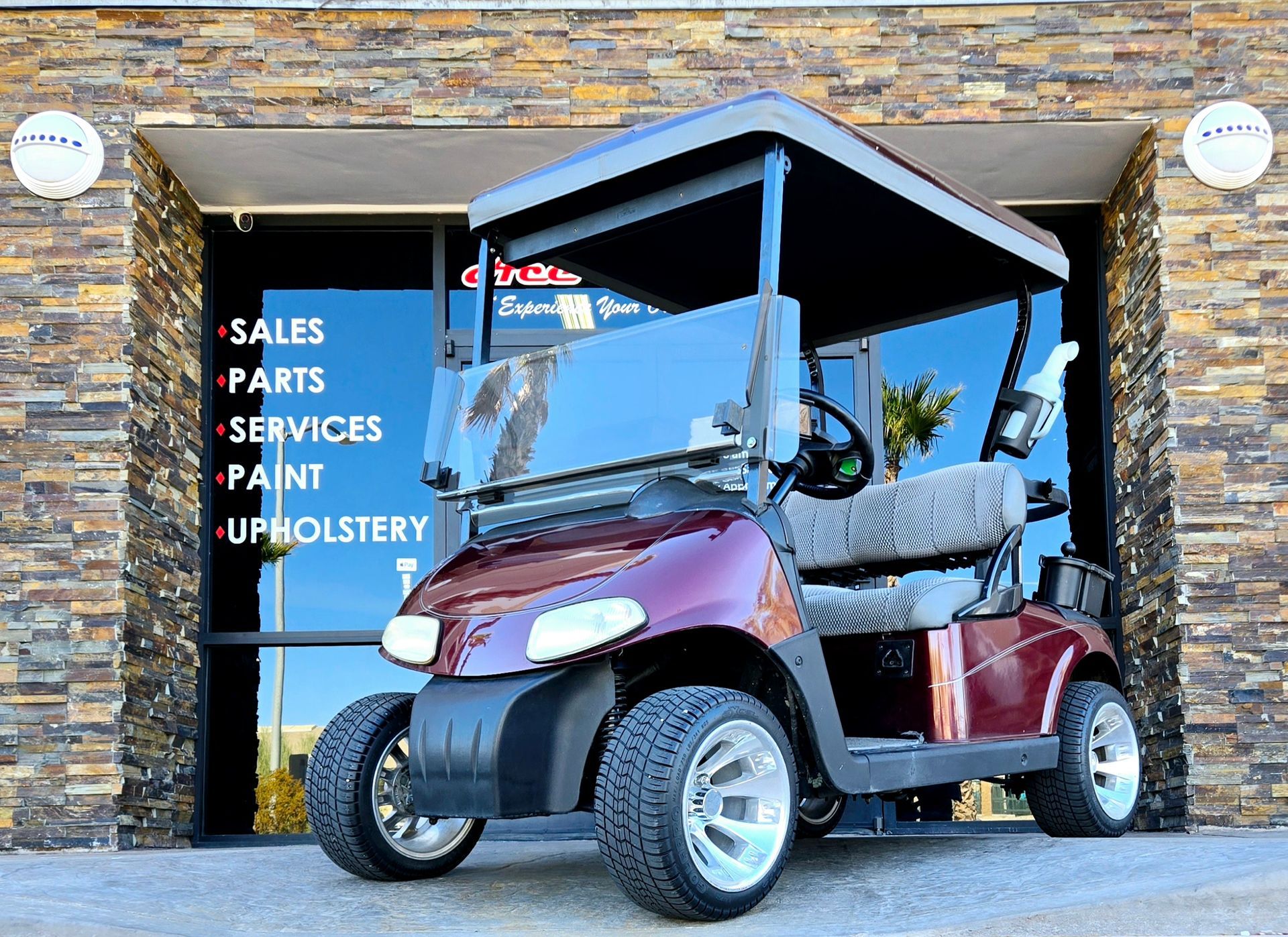 A red golf cart is parked in front of a brick building.
