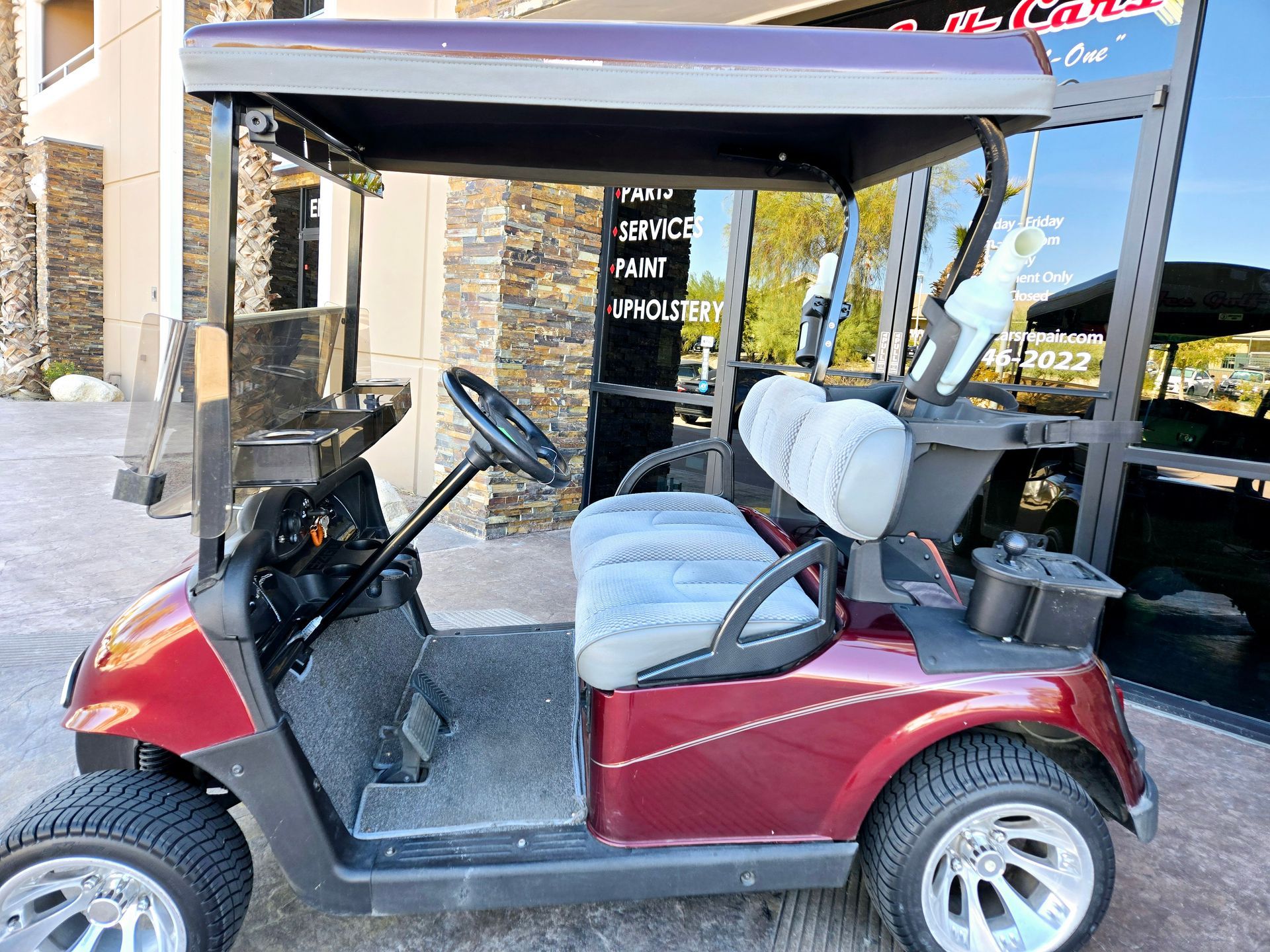 A red golf cart is parked in front of a building.