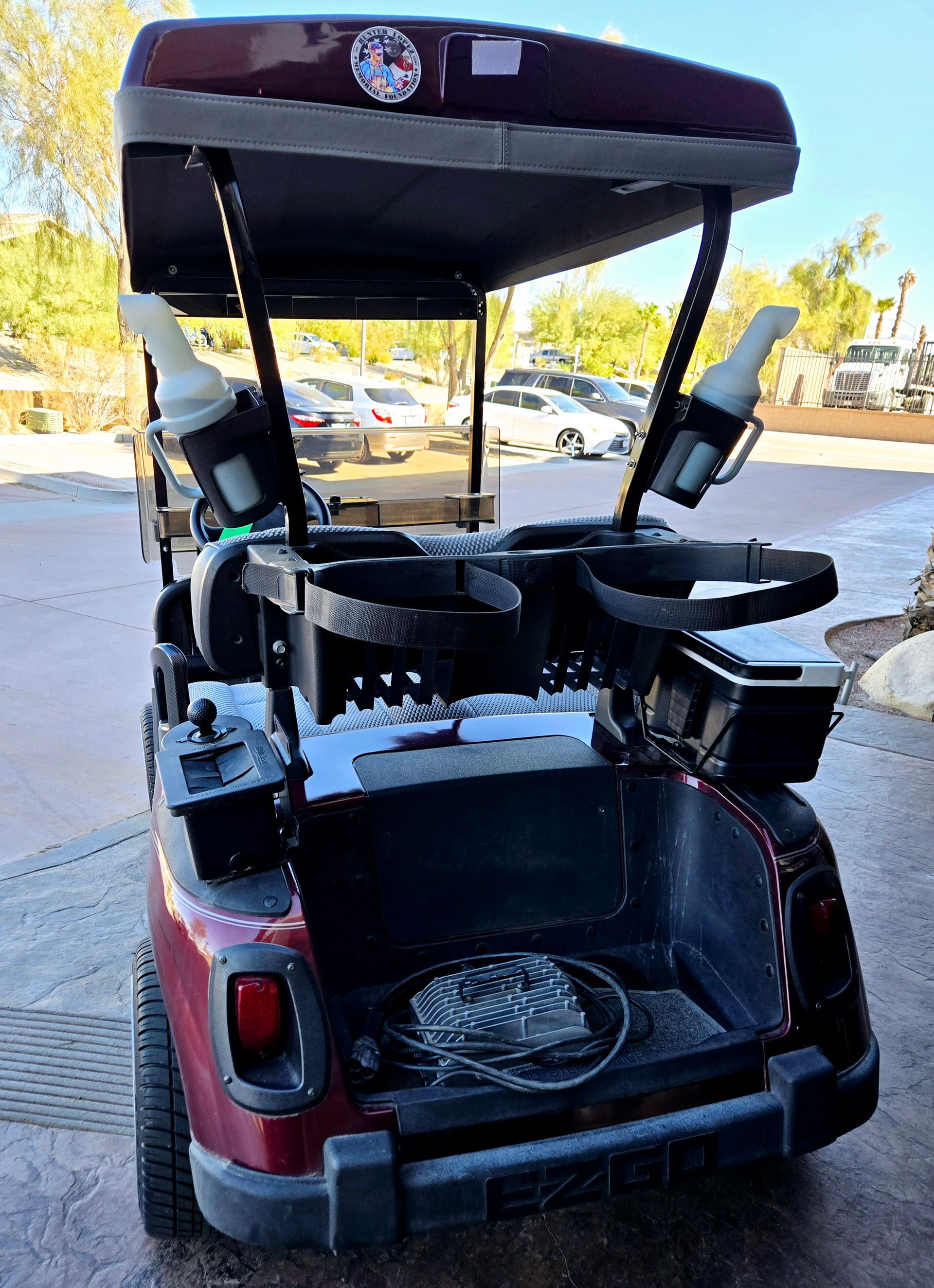 A red golf cart with the trunk open is parked in a parking lot.