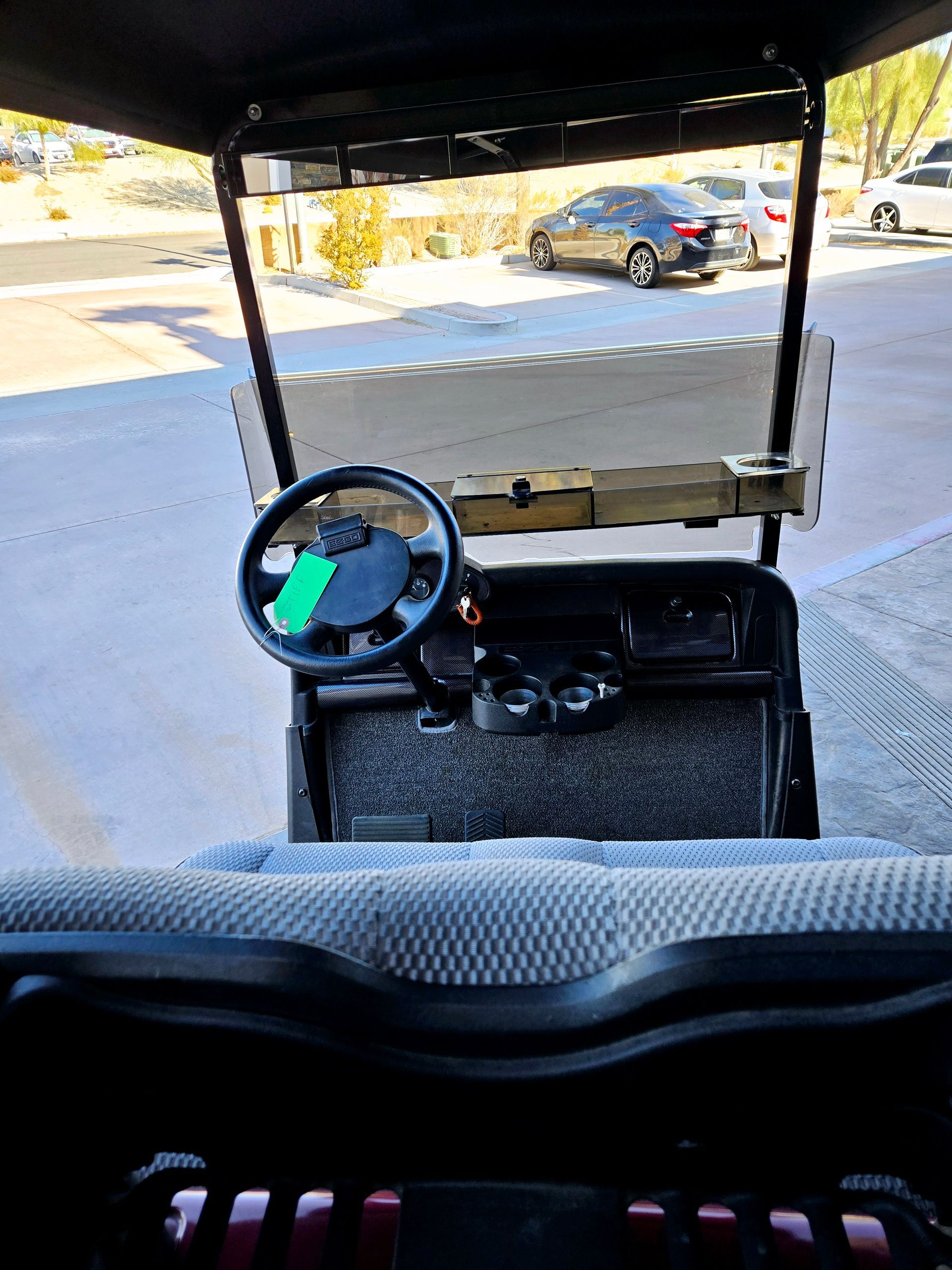 The inside of a golf cart with a green tag on the steering wheel.