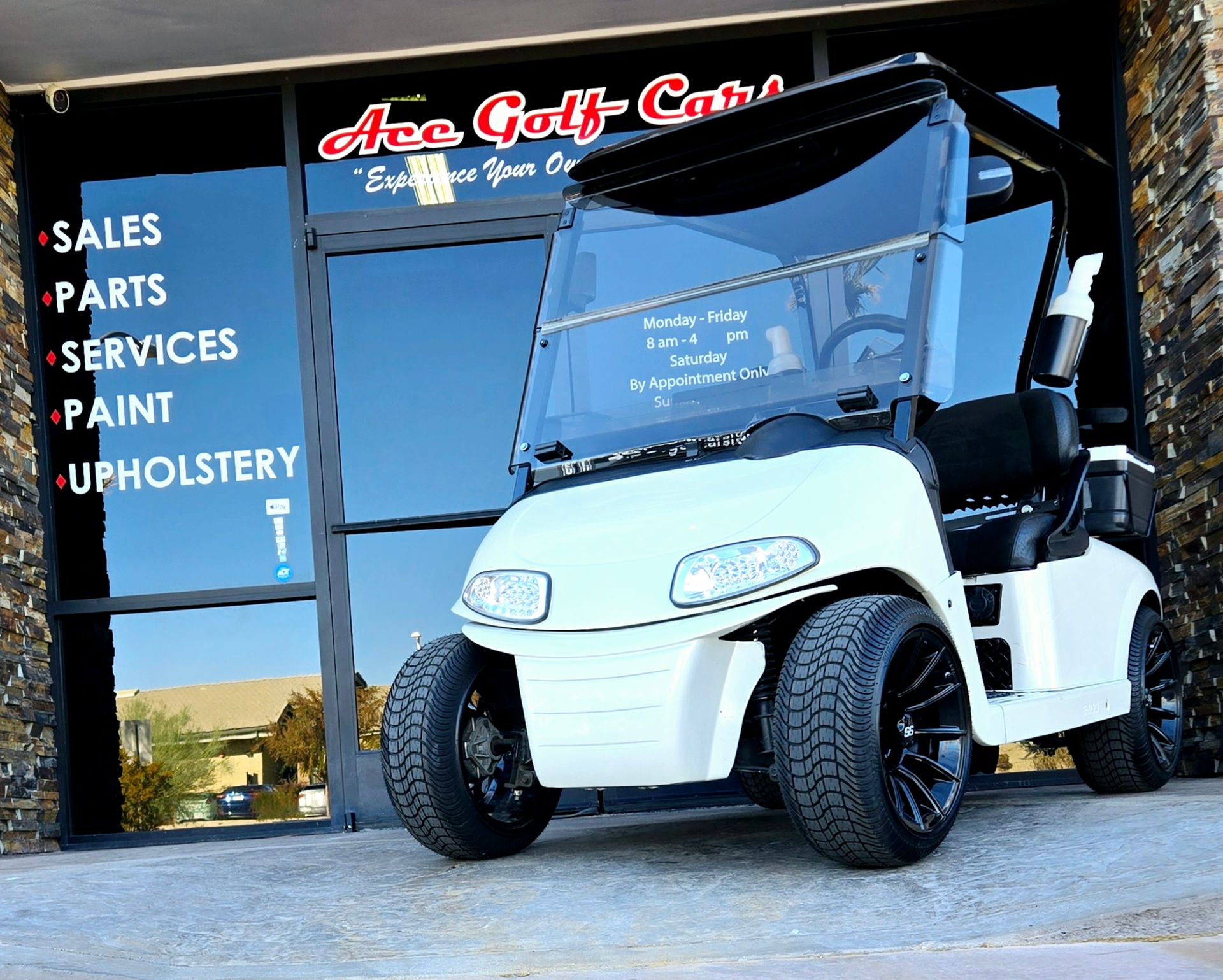 A white golf cart is parked in front of ace golf cars