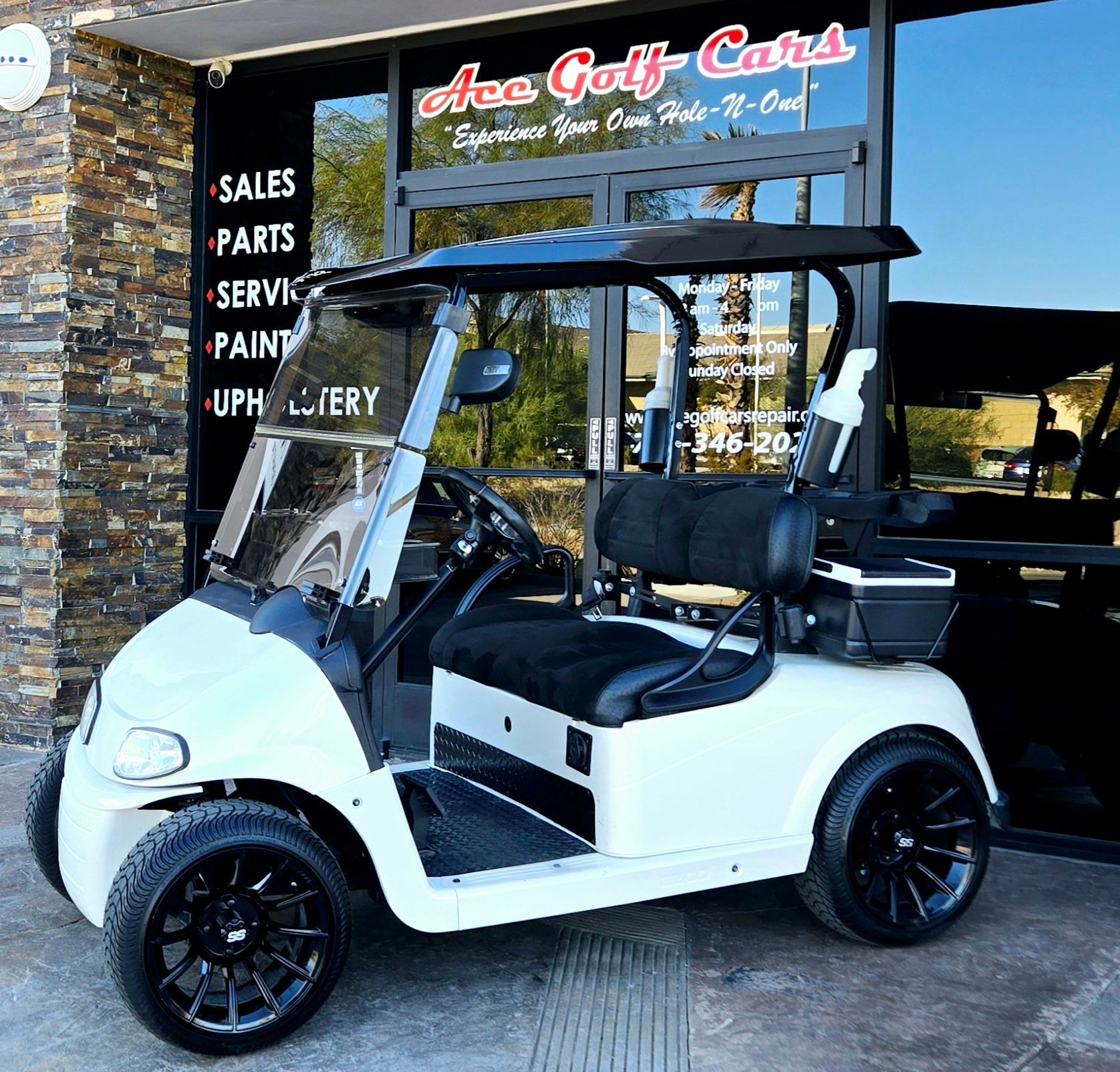 A white golf cart is parked in front of a store that sells golf carts