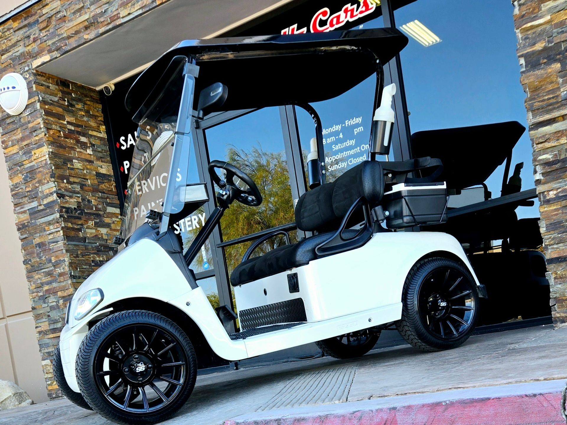 A white golf cart is parked in front of a building.