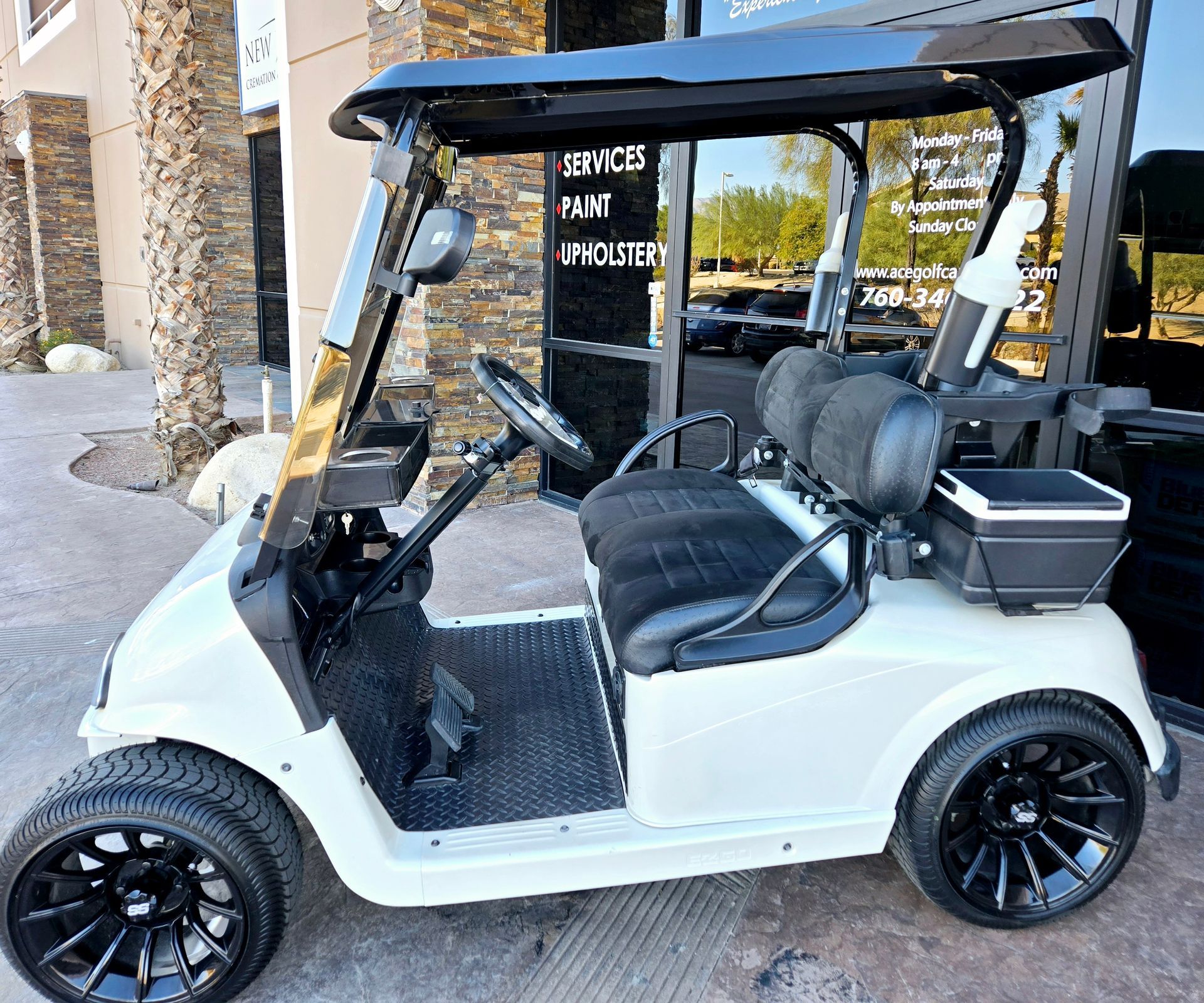 A white golf cart is parked in front of a building.