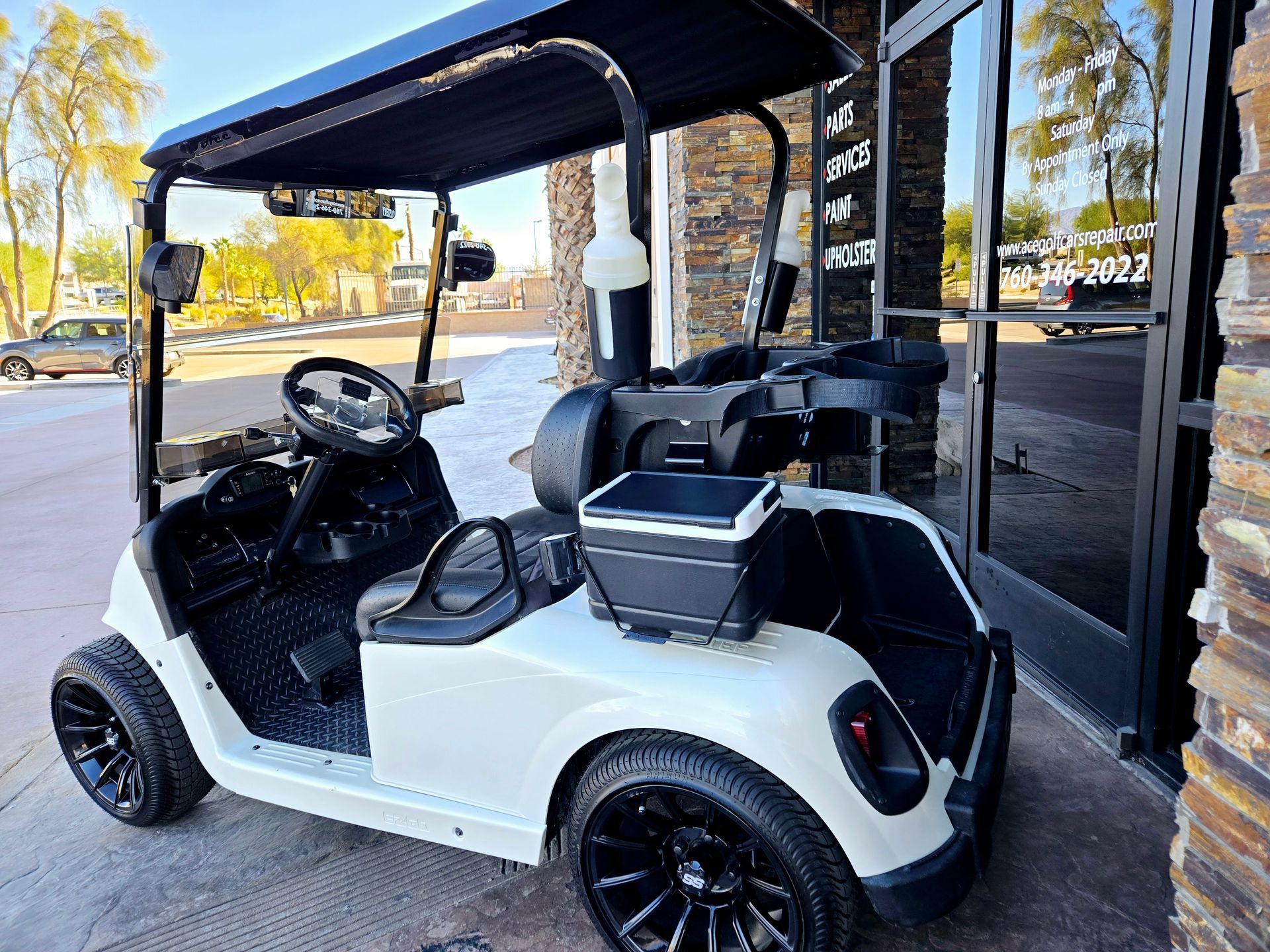A white golf cart is parked in front of a building.