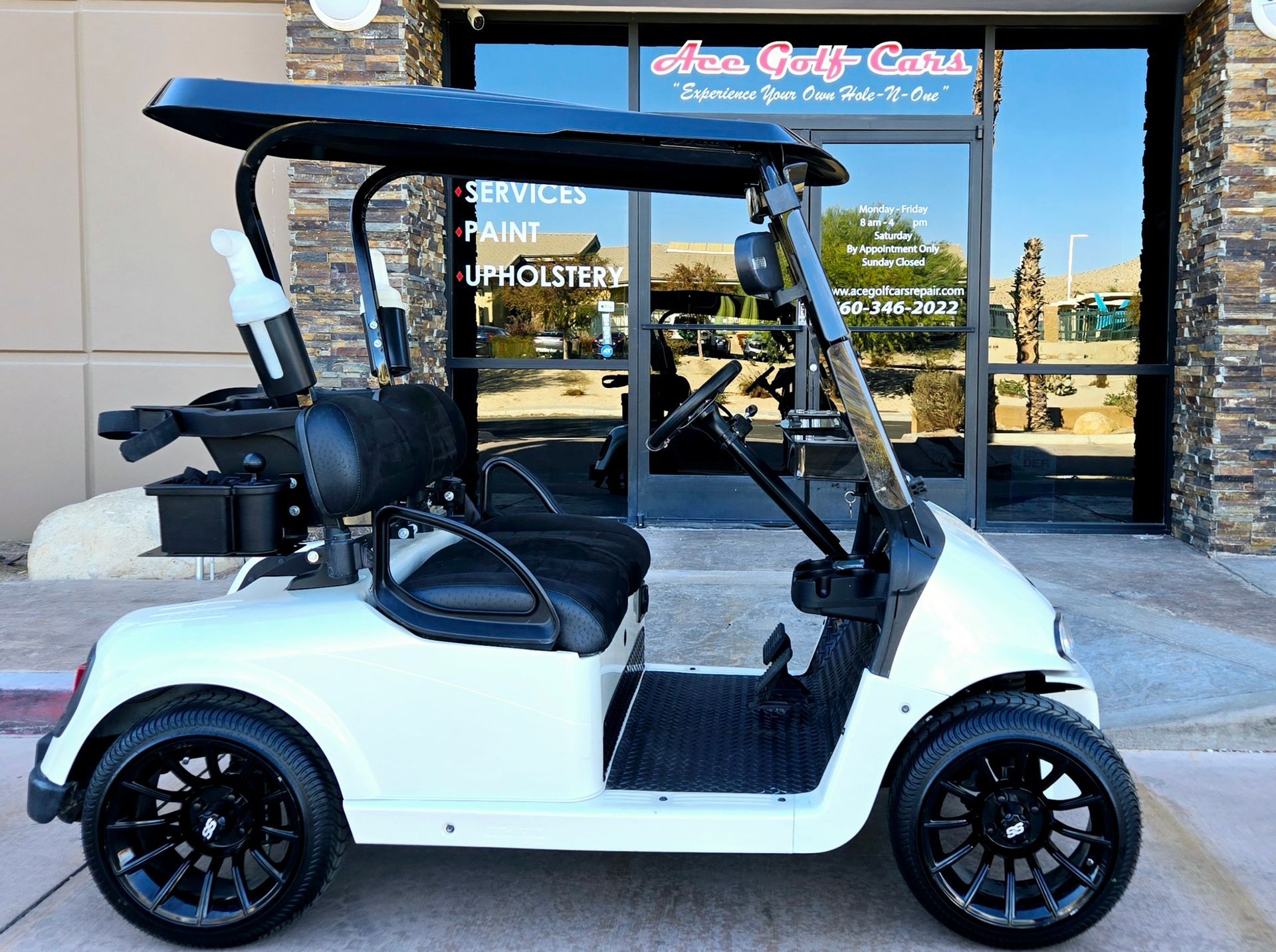 A white golf cart is parked in front of a building.