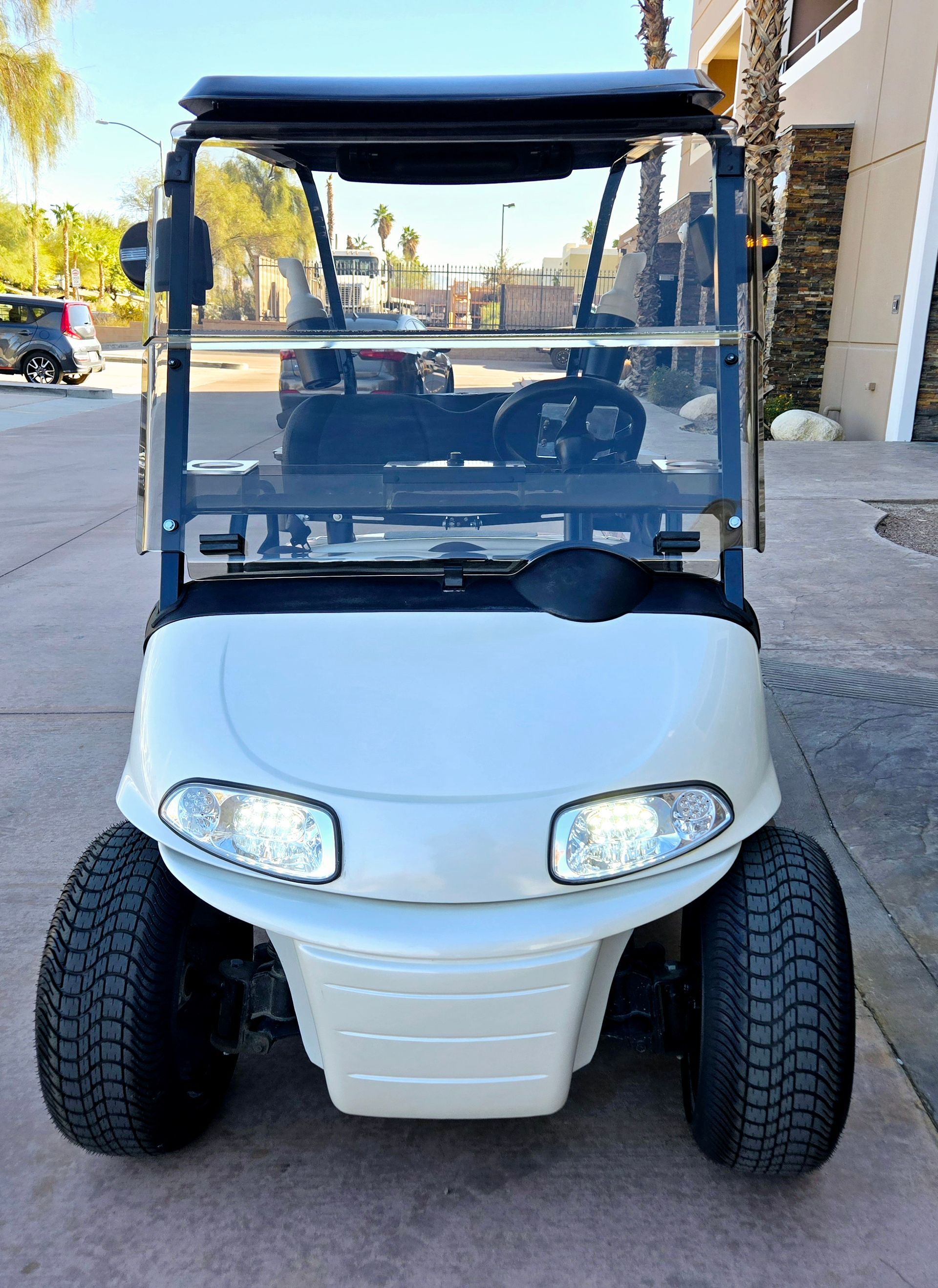A white golf cart is parked on the side of the road.