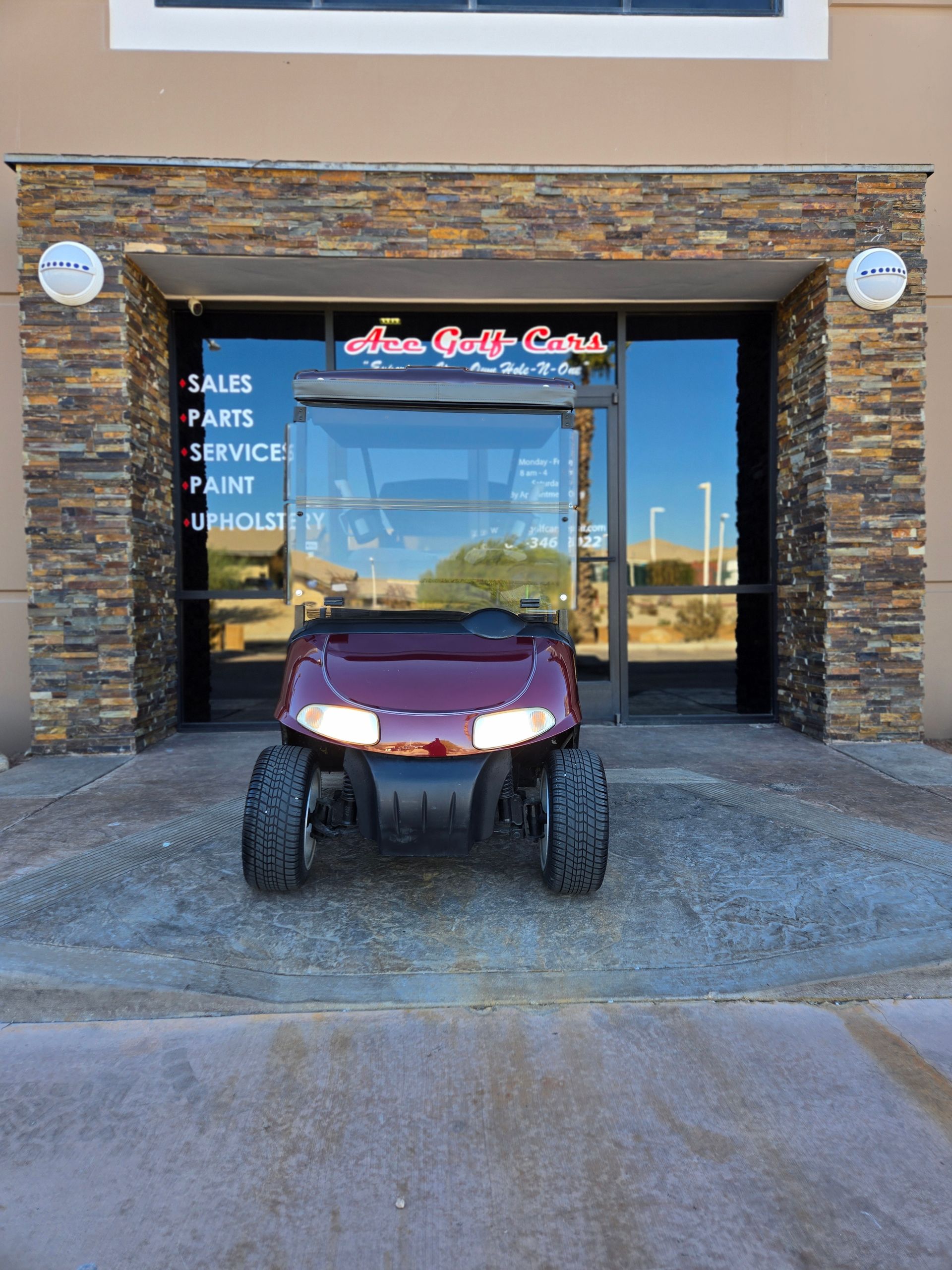 A red golf cart is parked in front of a building.