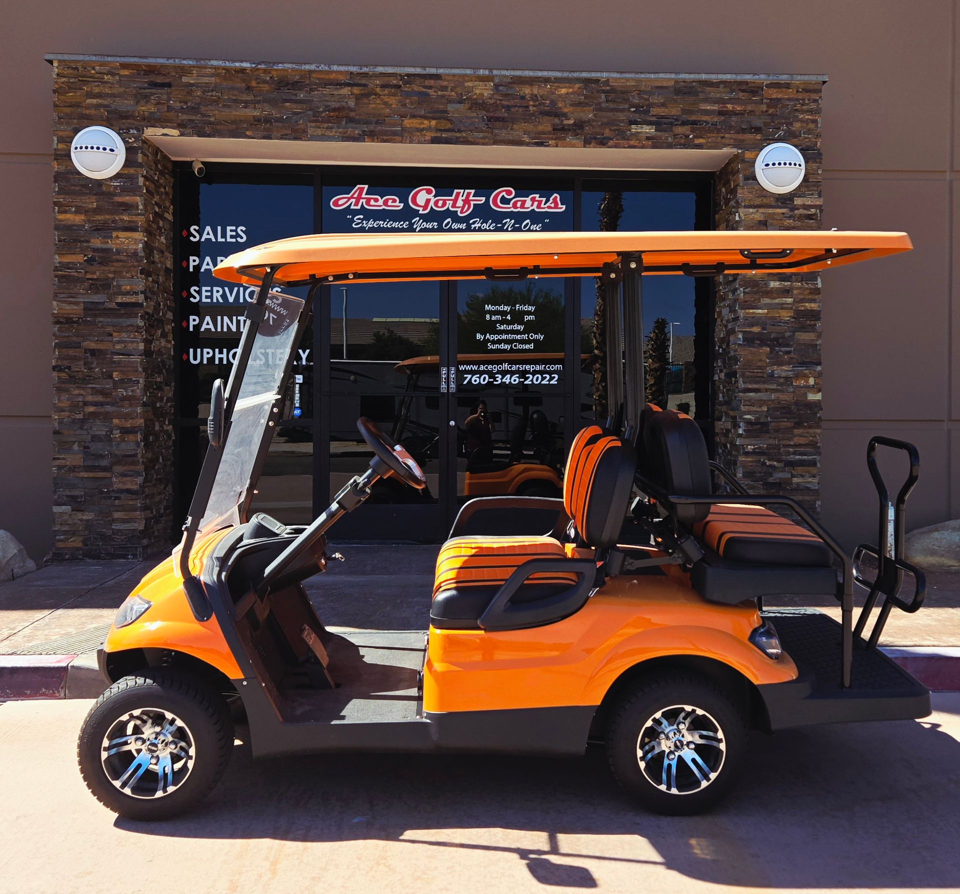 An orange golf cart is parked in front of a store