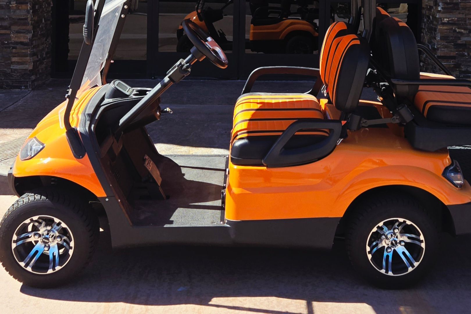 An orange golf cart is parked in front of a building