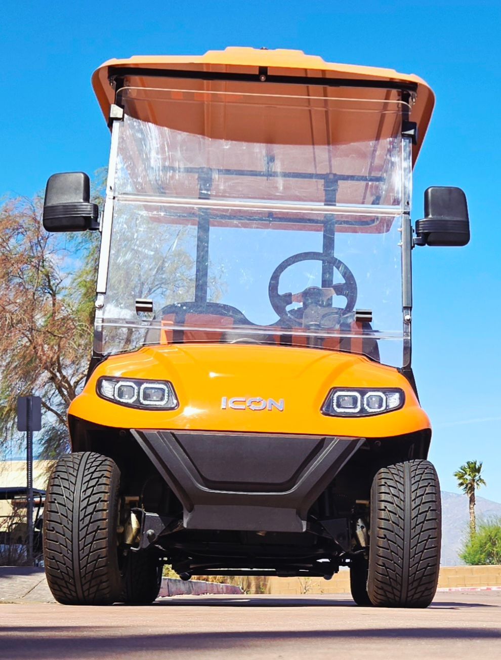 An orange golf cart is parked on the side of the road