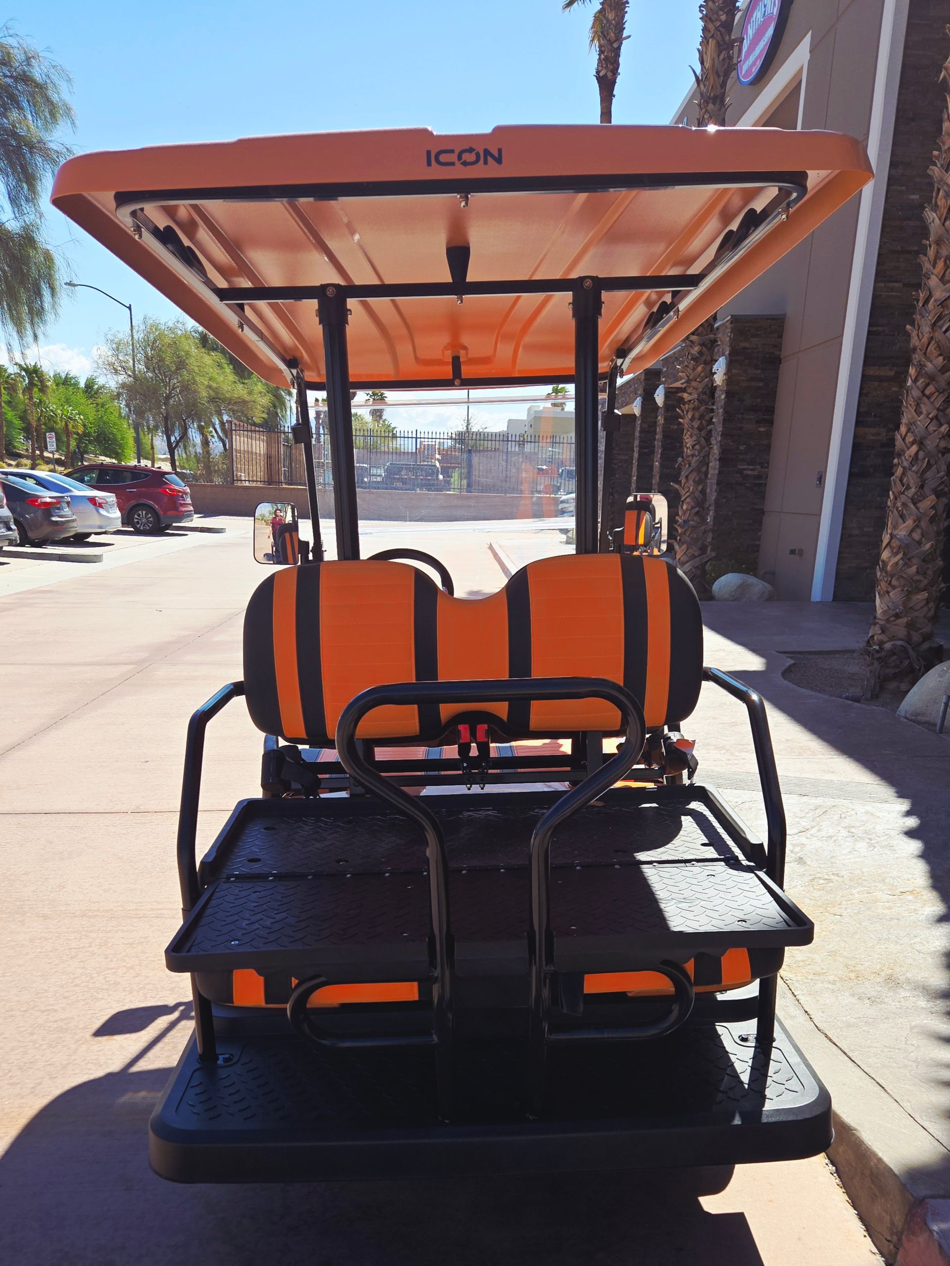 An orange icon golf cart is parked in a parking lot