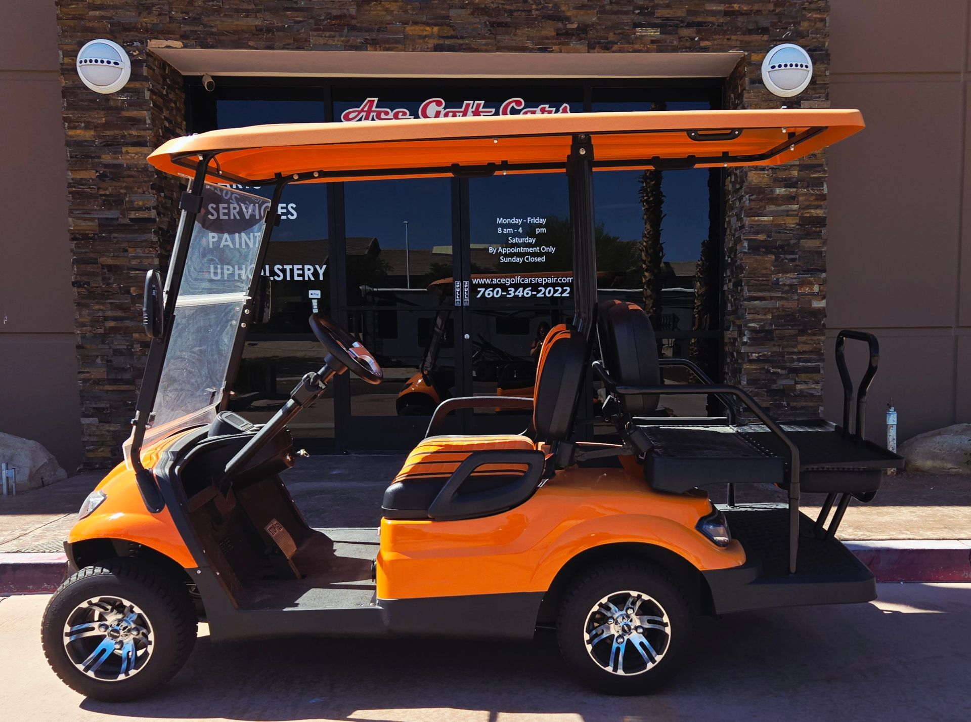An orange golf cart is parked in front of a building