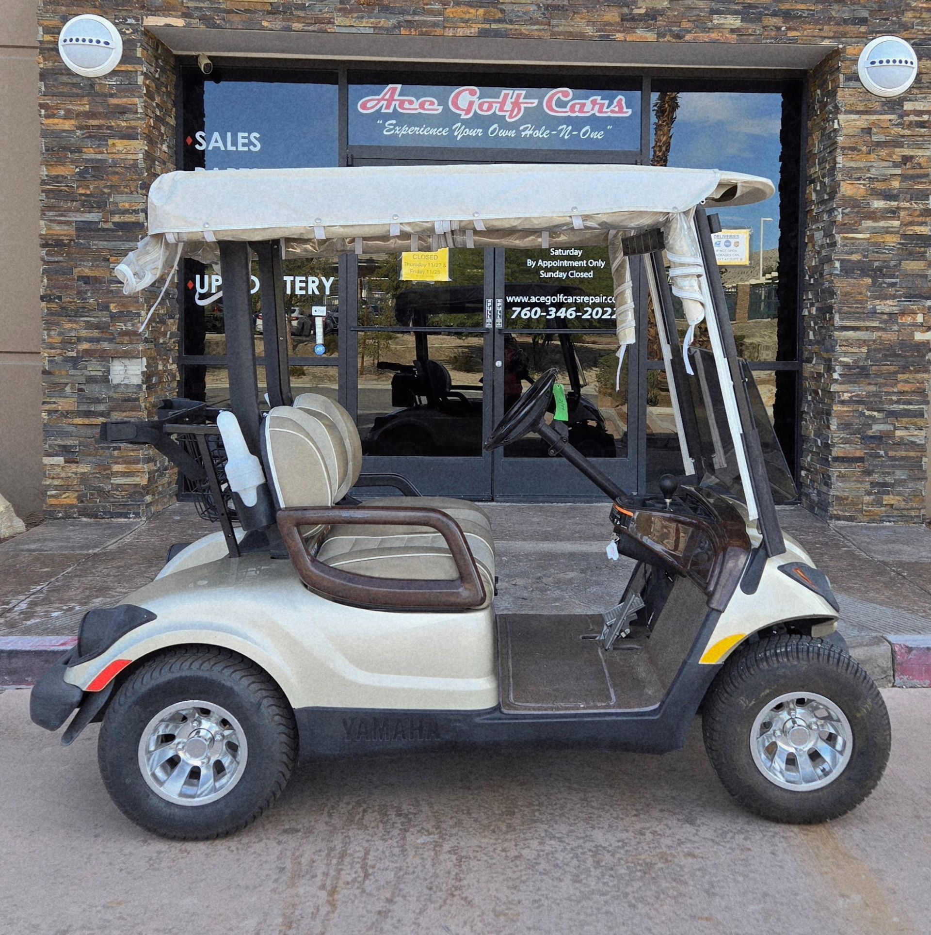 Tan golf cart parked in front of a golf cart sales business.
