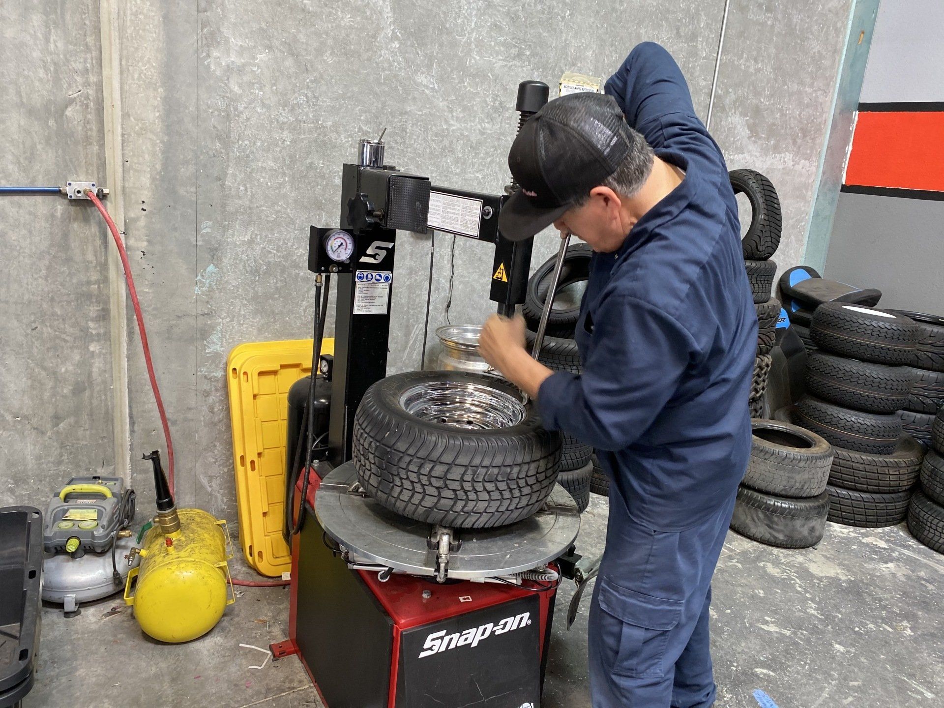 A man is working on a tire on a machine in a garage.