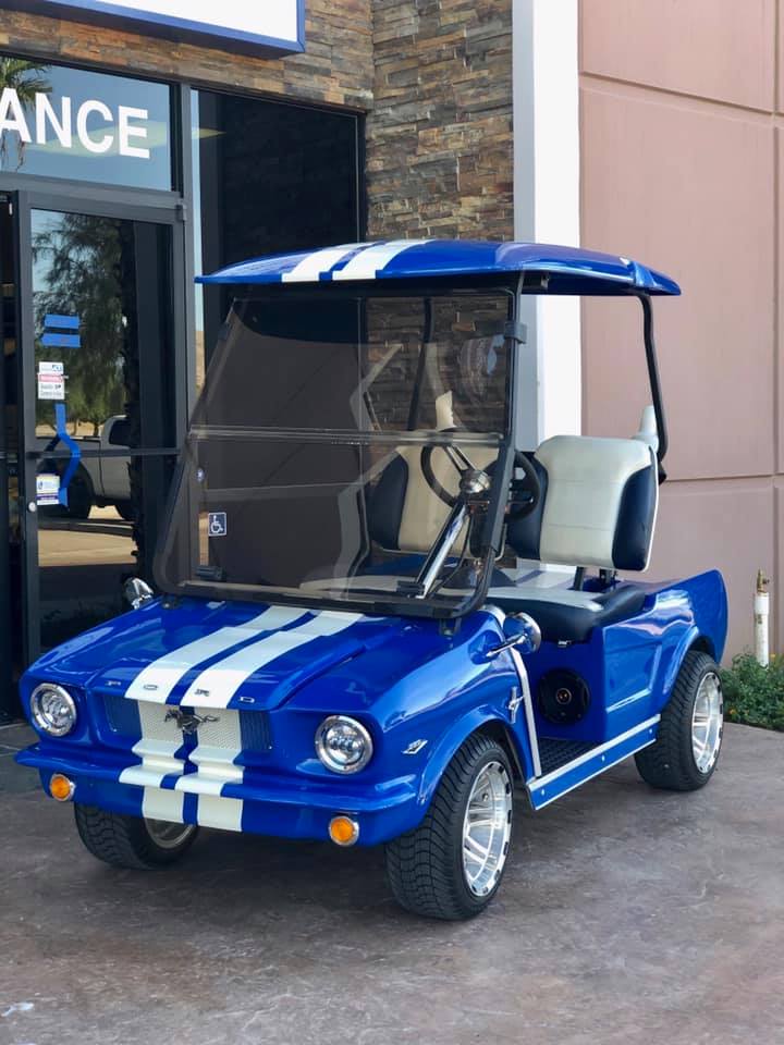 A blue and white golf cart is parked in front of a building.
