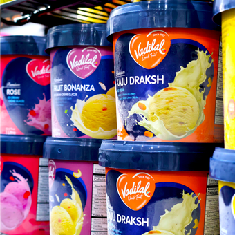 Several containers of vadilal ice cream are lined up on a shelf