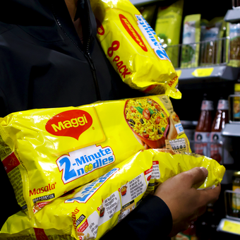 A person is holding two bags of maggi 2 minute noodles