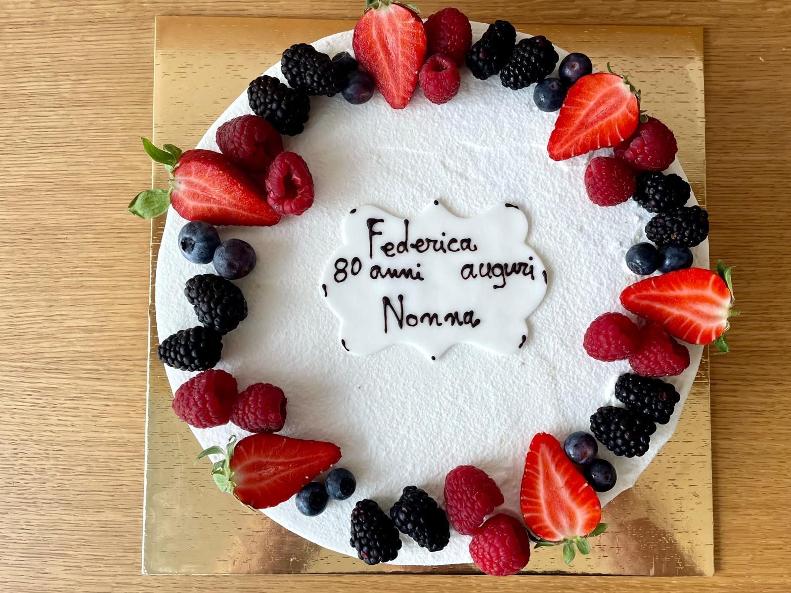 Torta decorata con frutti di bosco e scritta: 