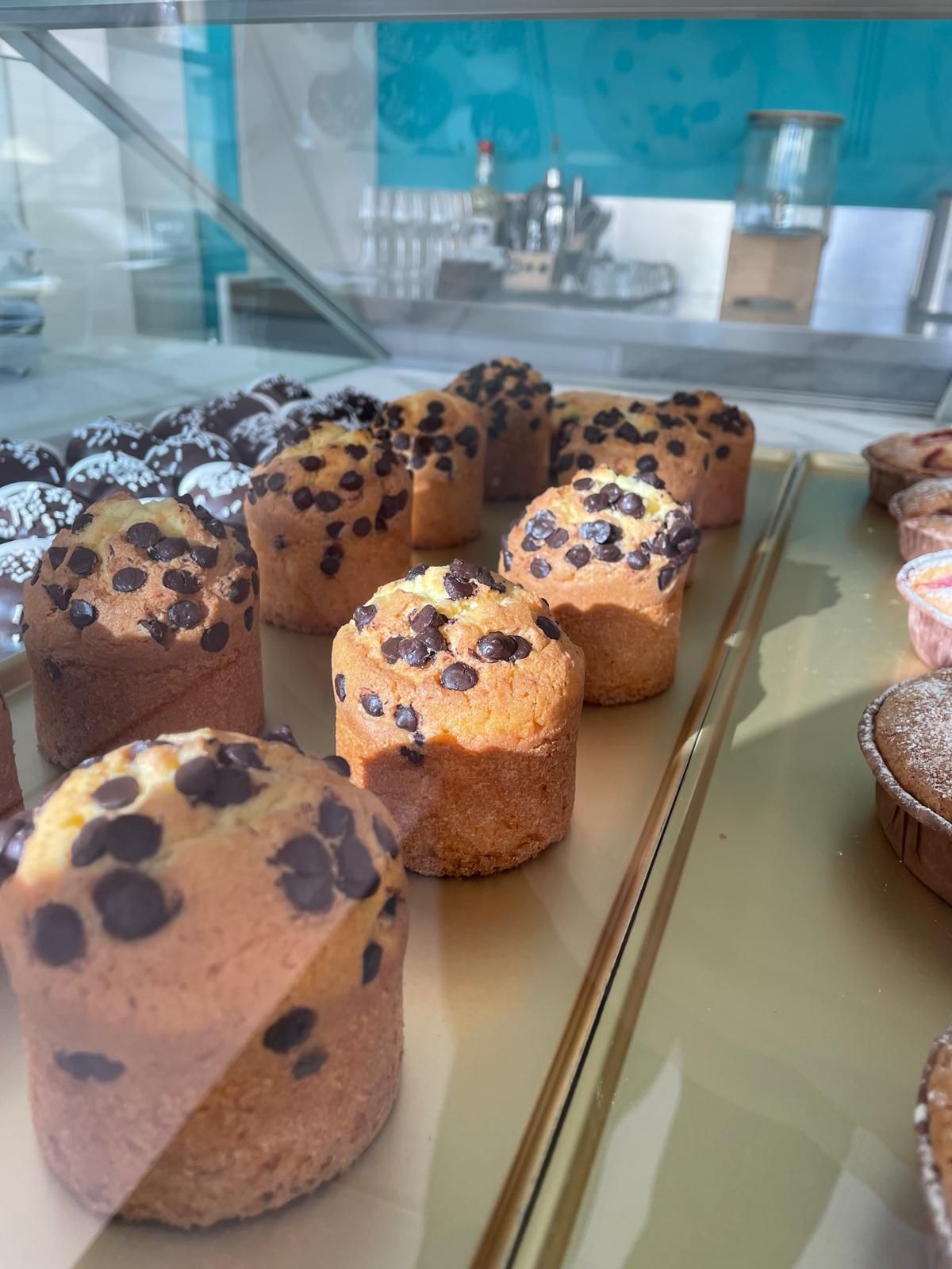 Muffin con gocce di cioccolato esposti in una vetrina di una panetteria.