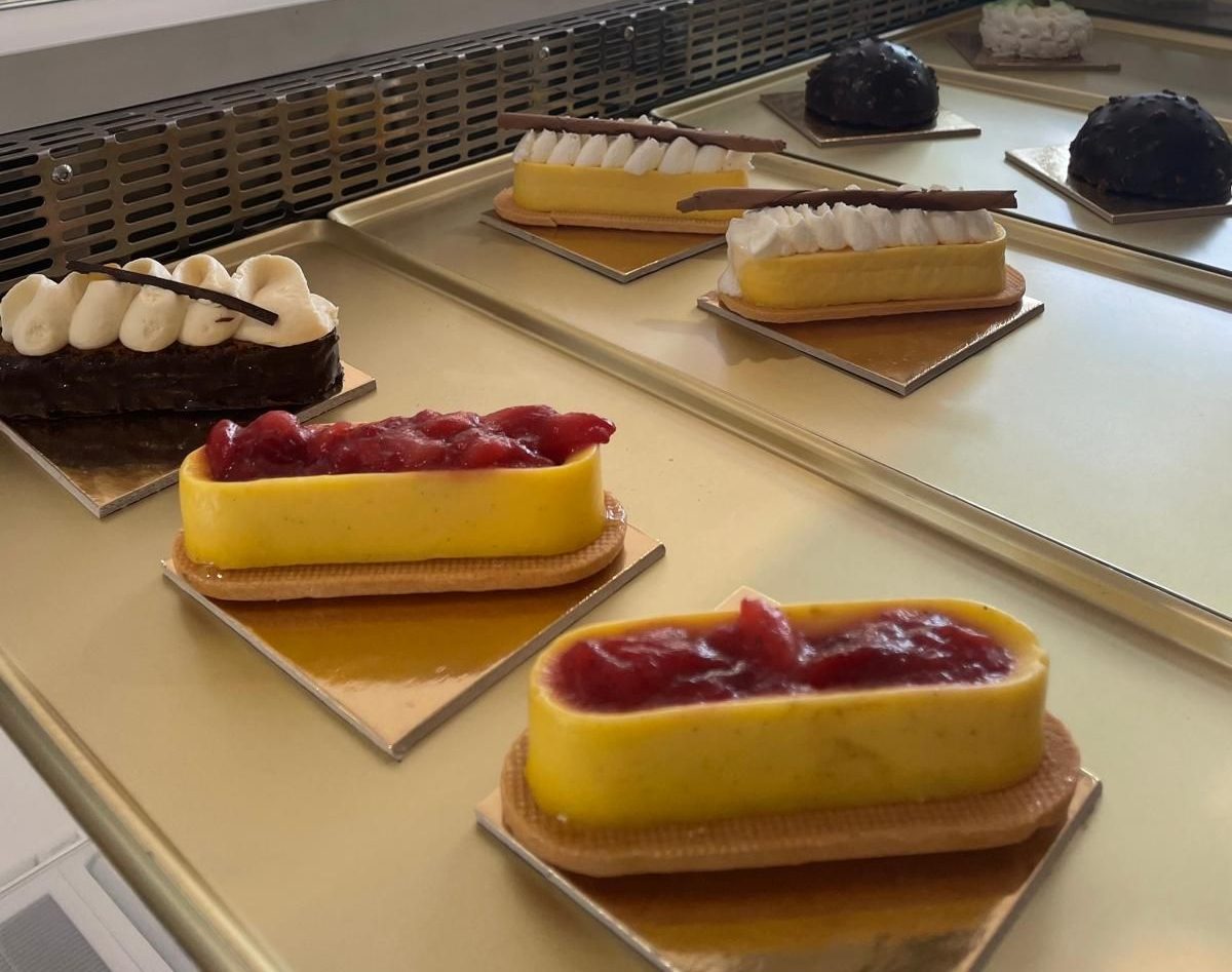 Pasticcini in esposizione: crostatine alla crema gialla con glassa rossa, torte al cioccolato con glassa bianca.