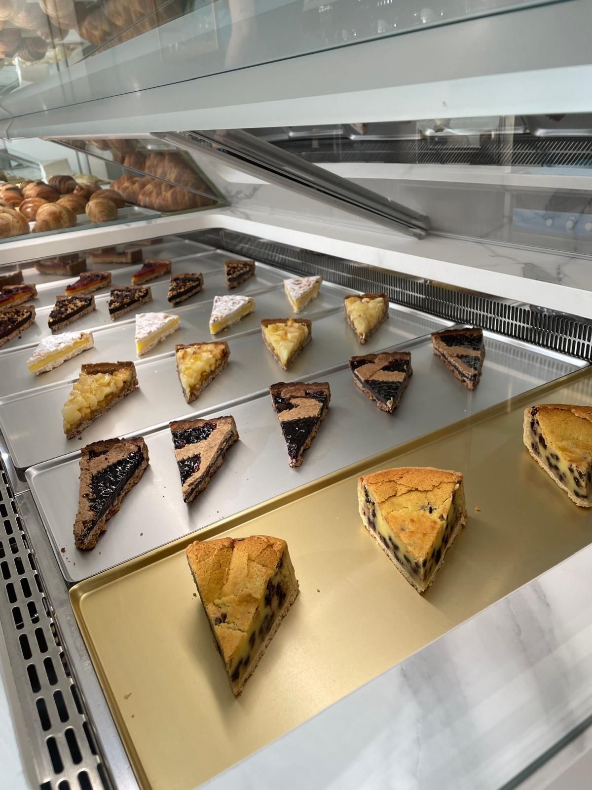 Pasticcini esposti in una vetrina di vetro: varie crostate e torte.