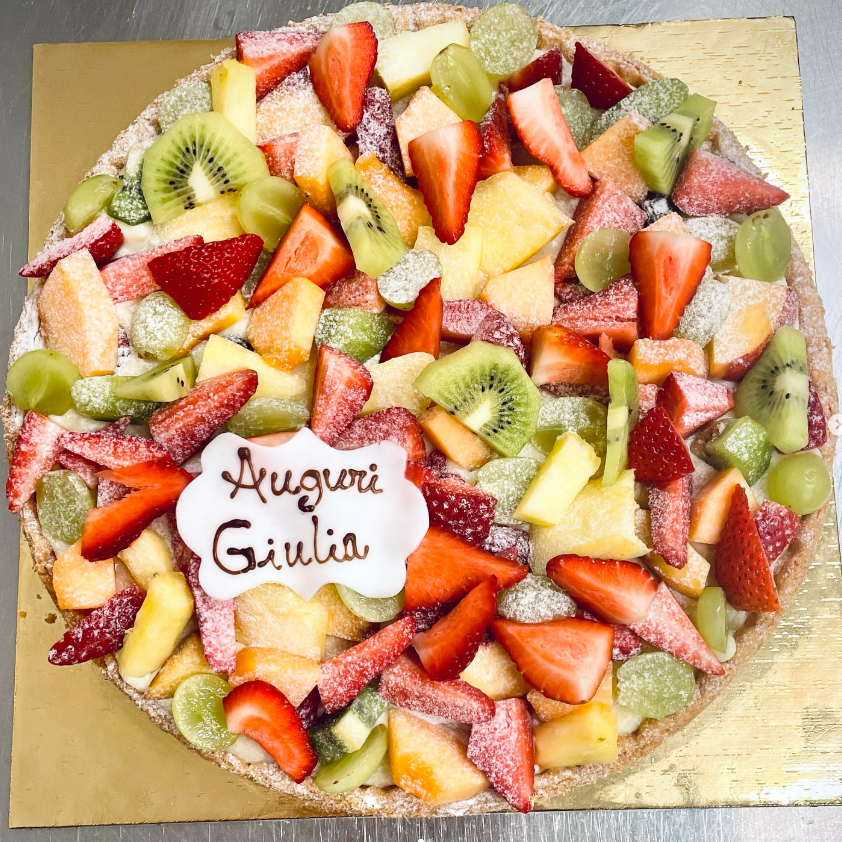 Crostata ai frutti di bosco con lamponi, mirtilli e gocce di cioccolato su una base dorata.