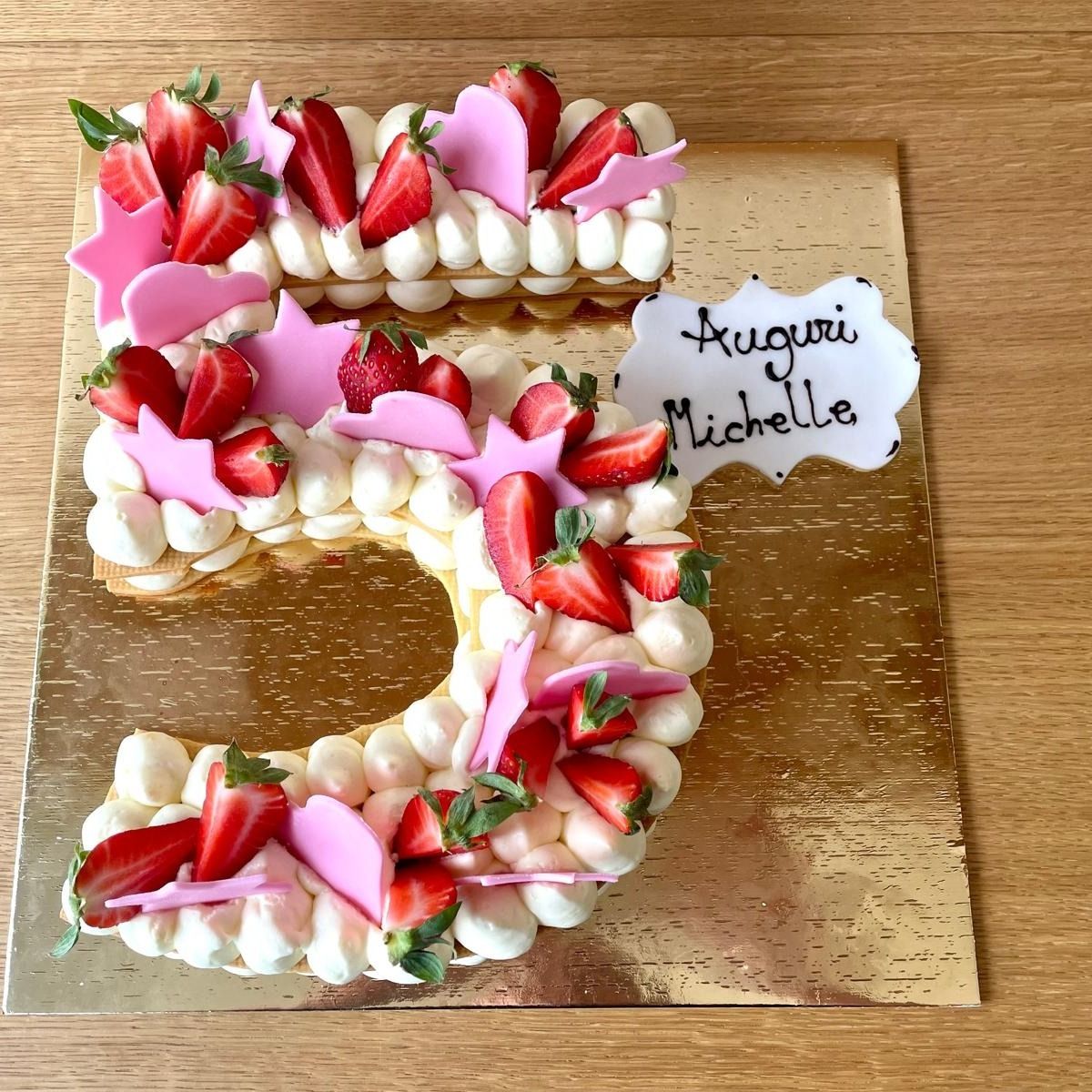 Torta numero 5 decorata con fragole e glassa su tavola dorata, 