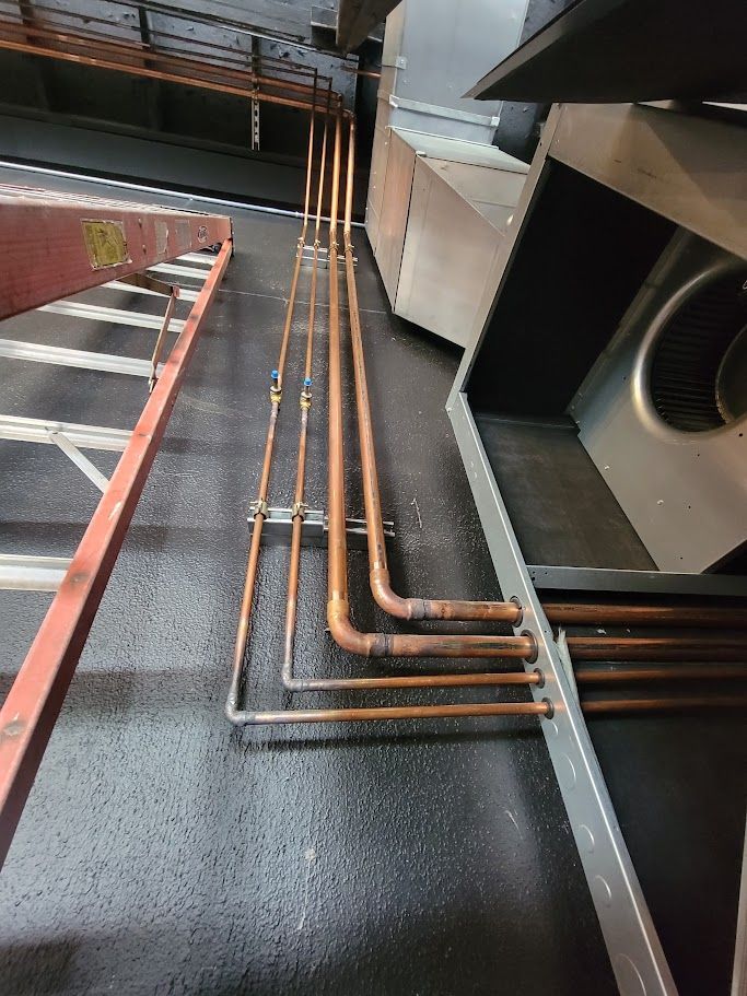 A bunch of copper pipes are connected to each other on the floor of a building.