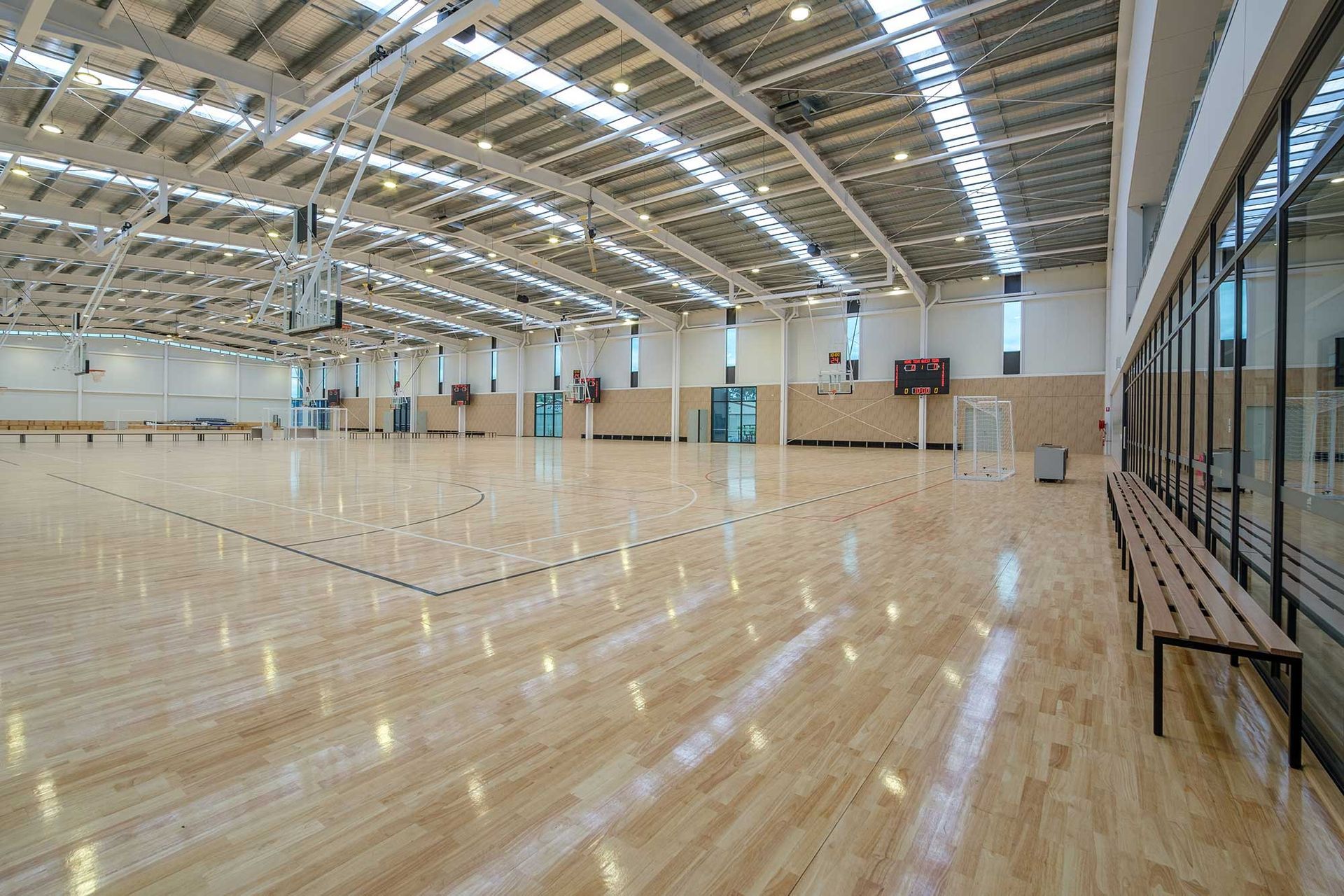A large indoor basketball court with a wooden floor and benches.