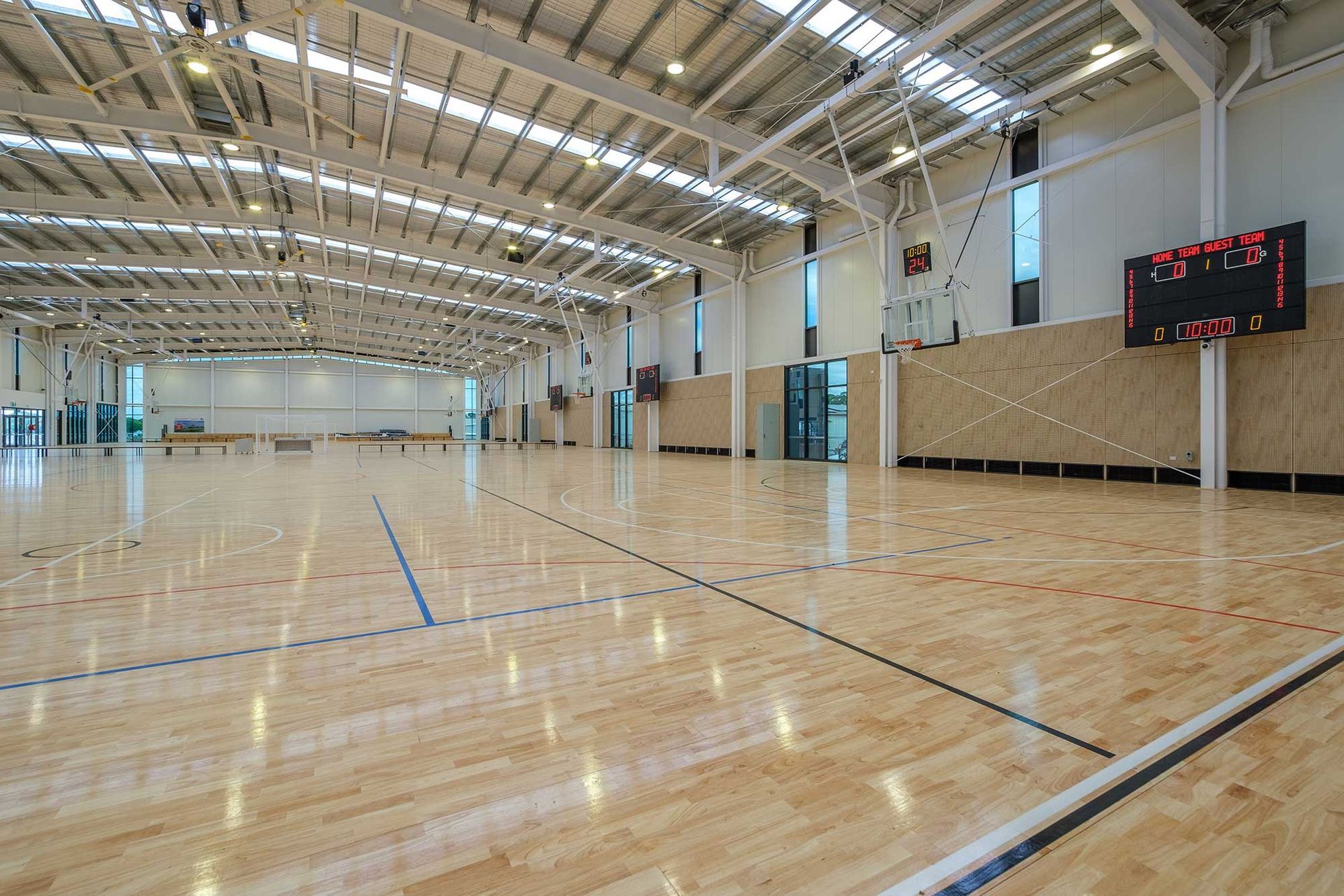 A large indoor basketball court with a wooden floor and a scoreboard.